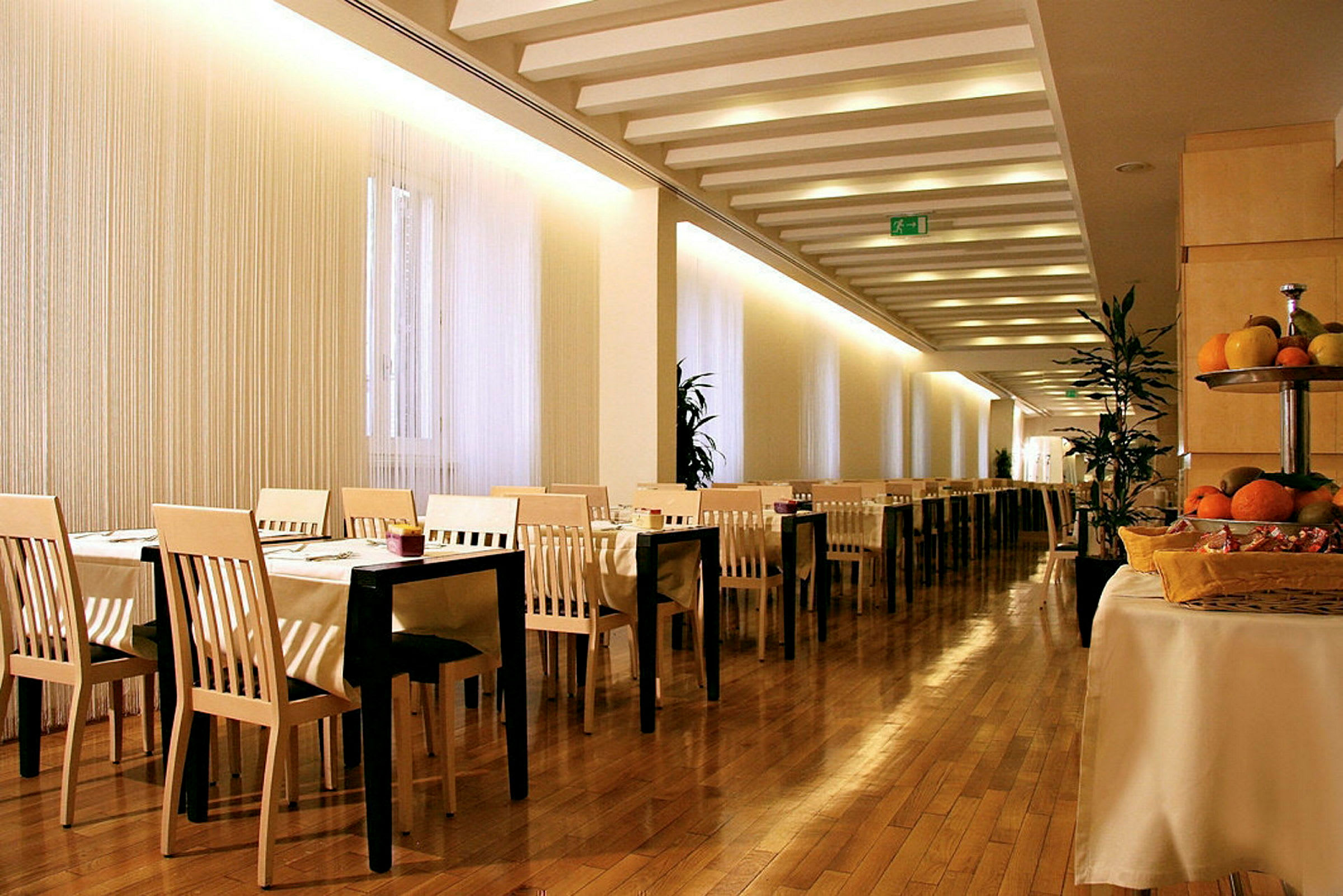 Bilde av en restaurant med bord og stoler, tregulv og frukt på et bord. (AI-generert tekst)