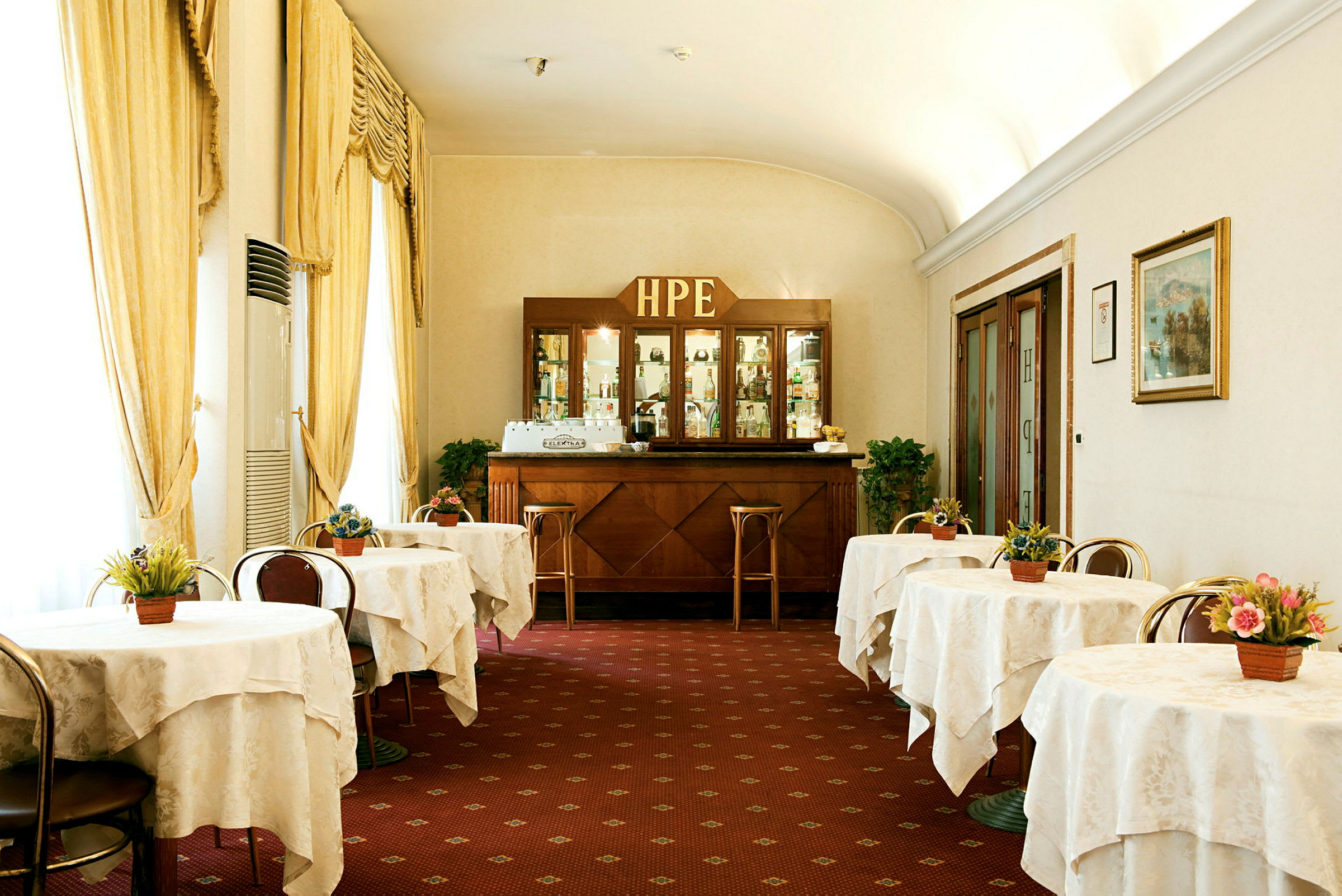 Bilde av et klassisk hotellkafémiljø med dekkede bord og en trebar i bakgrunnen. (AI-generert tekst)