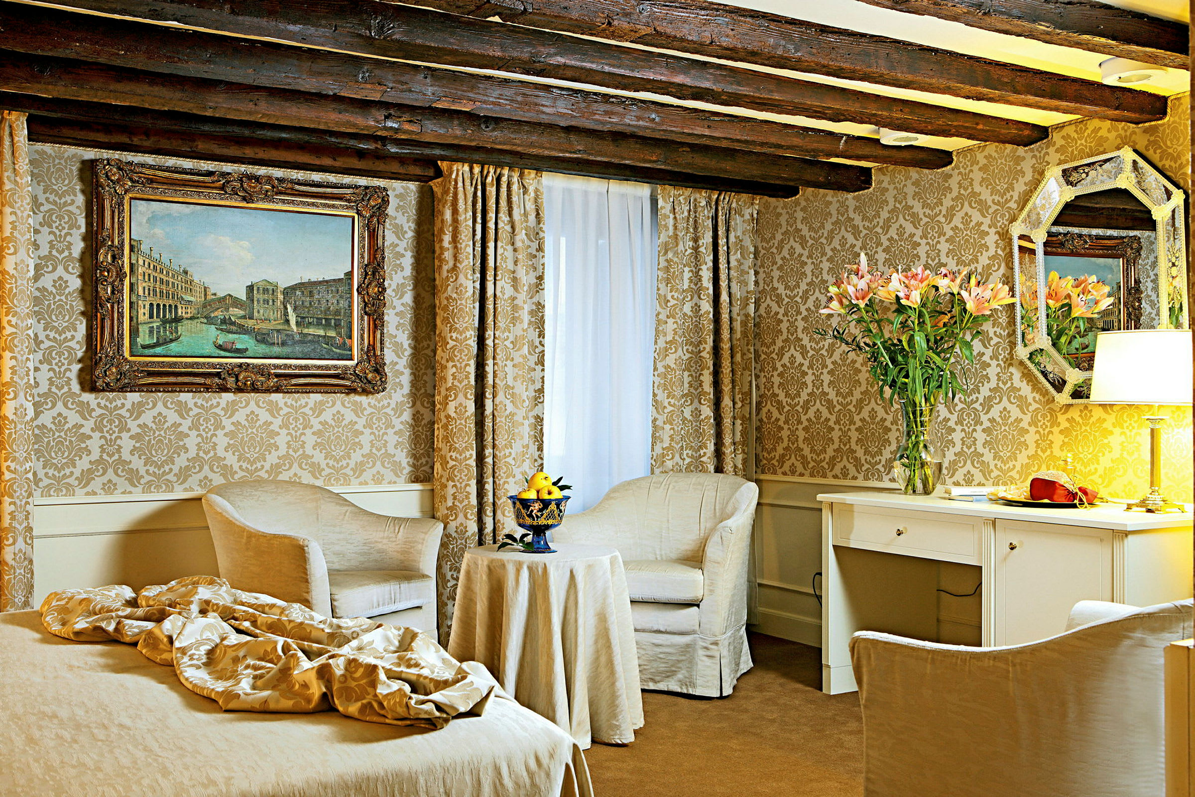Et elegant hotellrom med klassisk innredning inkludert to stoler, bord, skrivebord og veggdekorasjoner. (AI-generert tekst)