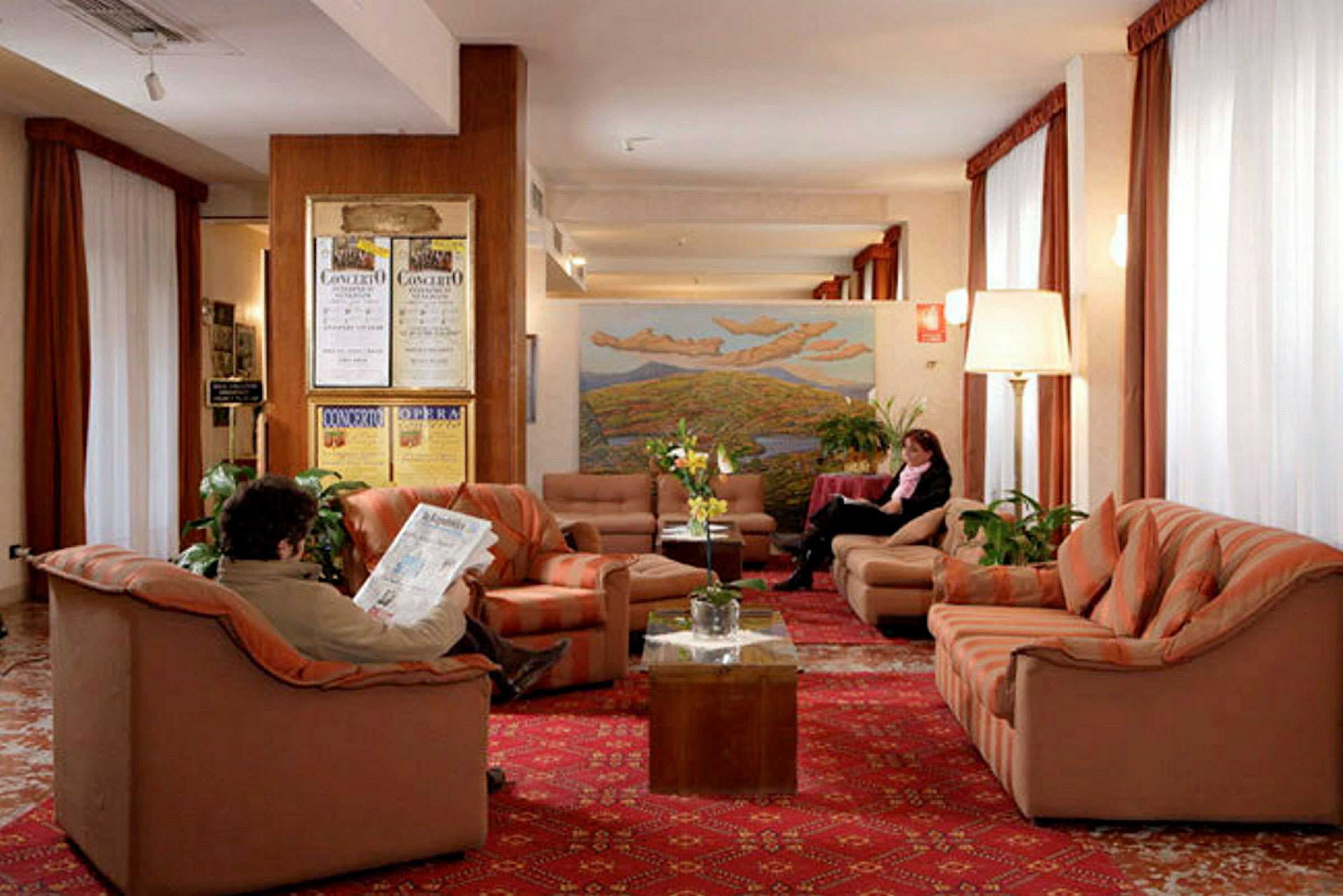 Bilde av en hotellobby med sofaer og lenestoler plassert på et rødt teppe. (AI-generert tekst)