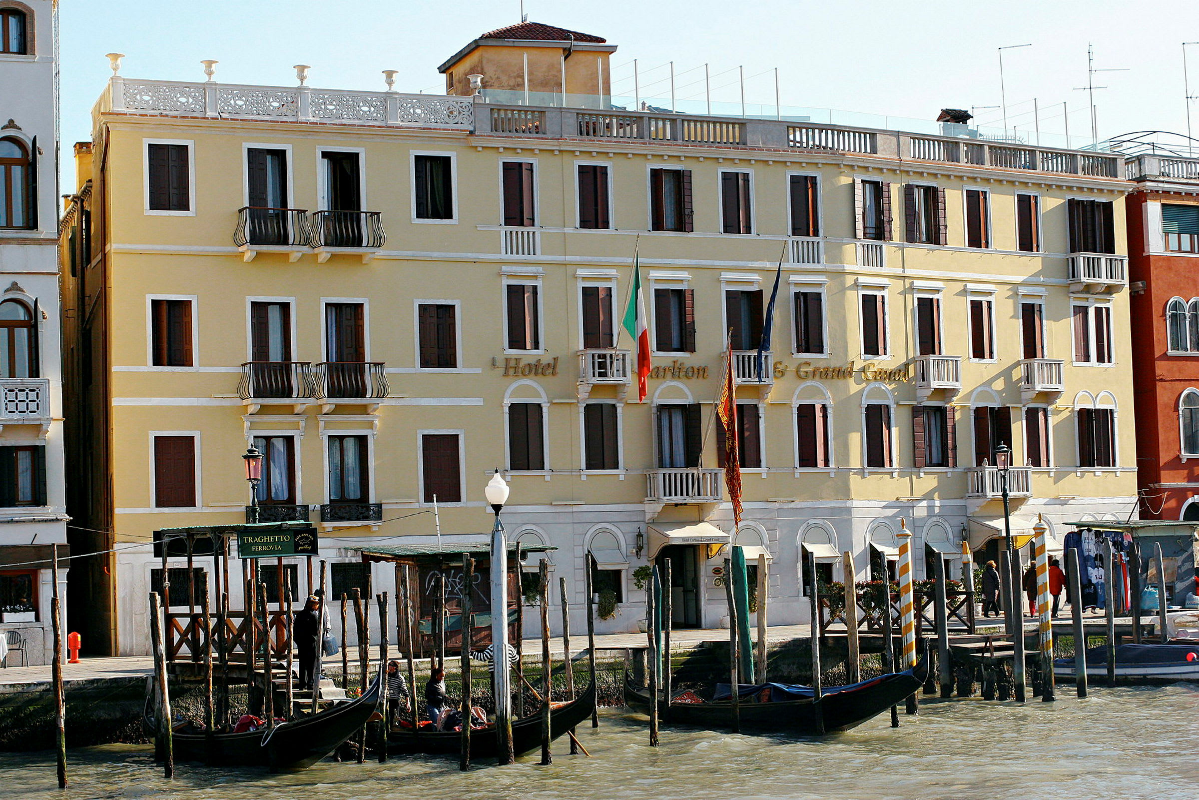 Et gult hotell ved Grand Canal i Venezia med gondoler foran. (AI-generert tekst)