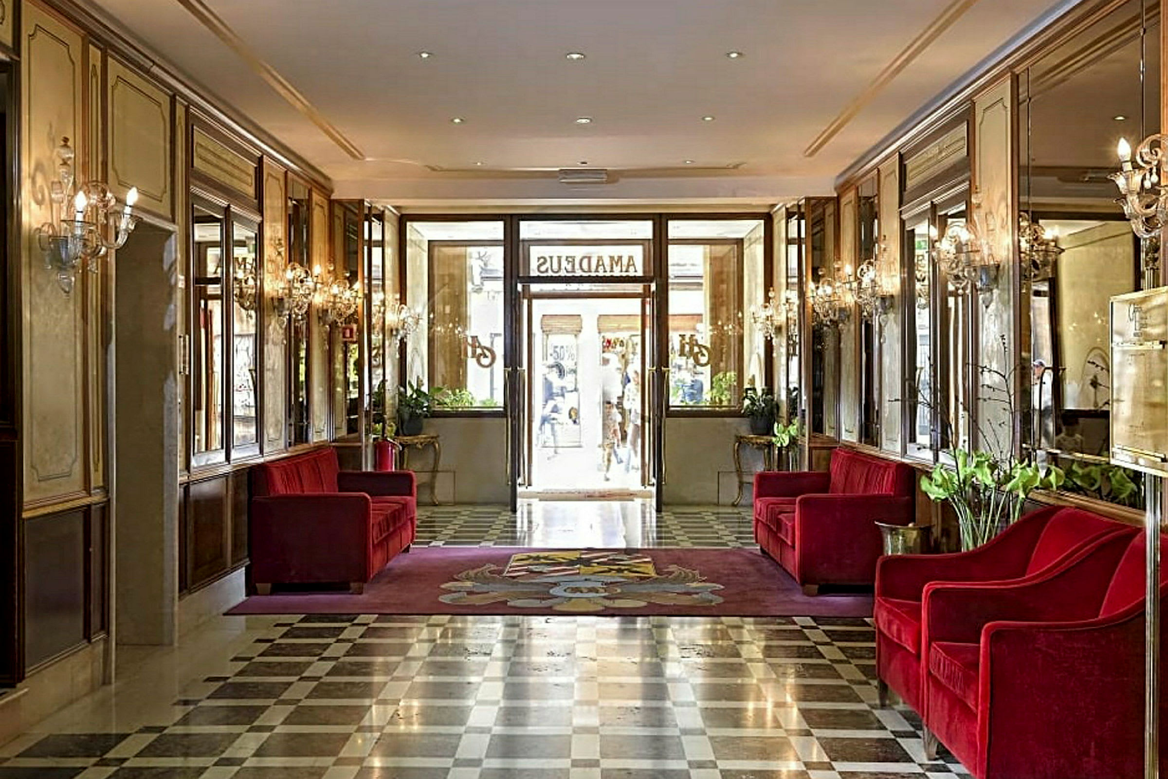 Hotellobby med røde sofaer og marmorgulv. (AI-generert tekst)