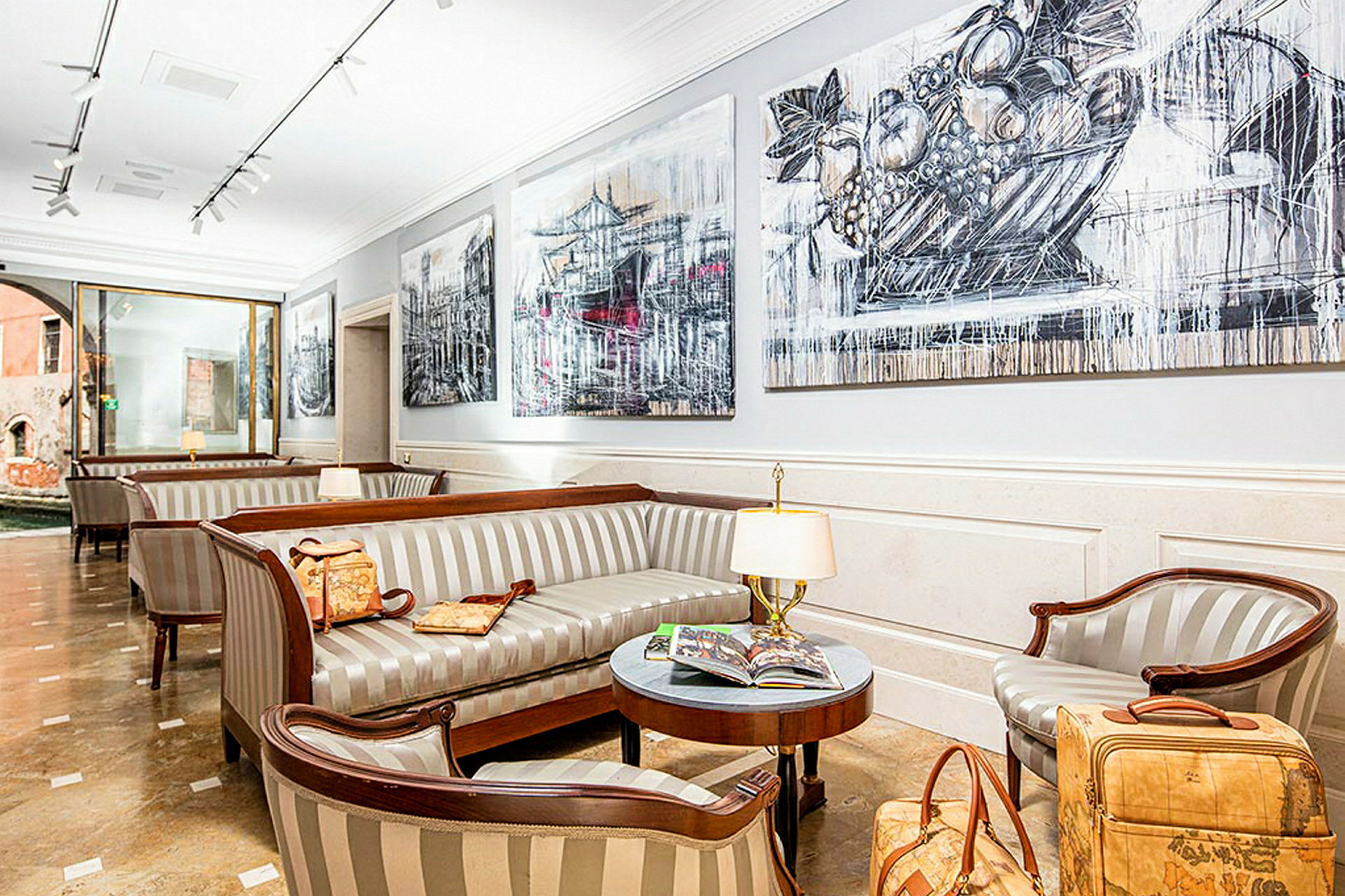 En elegant venterom i en hotellobby med stripete sofaer, et bord med magasiner og lamper samt veggdekorasjoner. (AI-generert tekst)