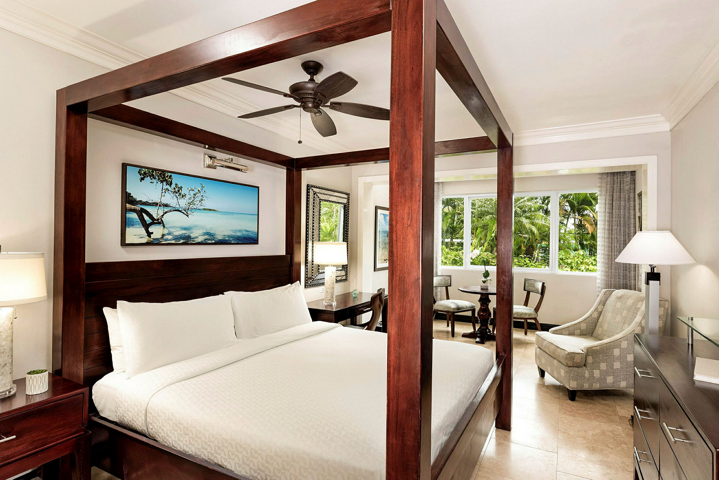 Et hotellrom med en himmelseng, en sittegruppe og et stort vindu. (AI-generert tekst)
