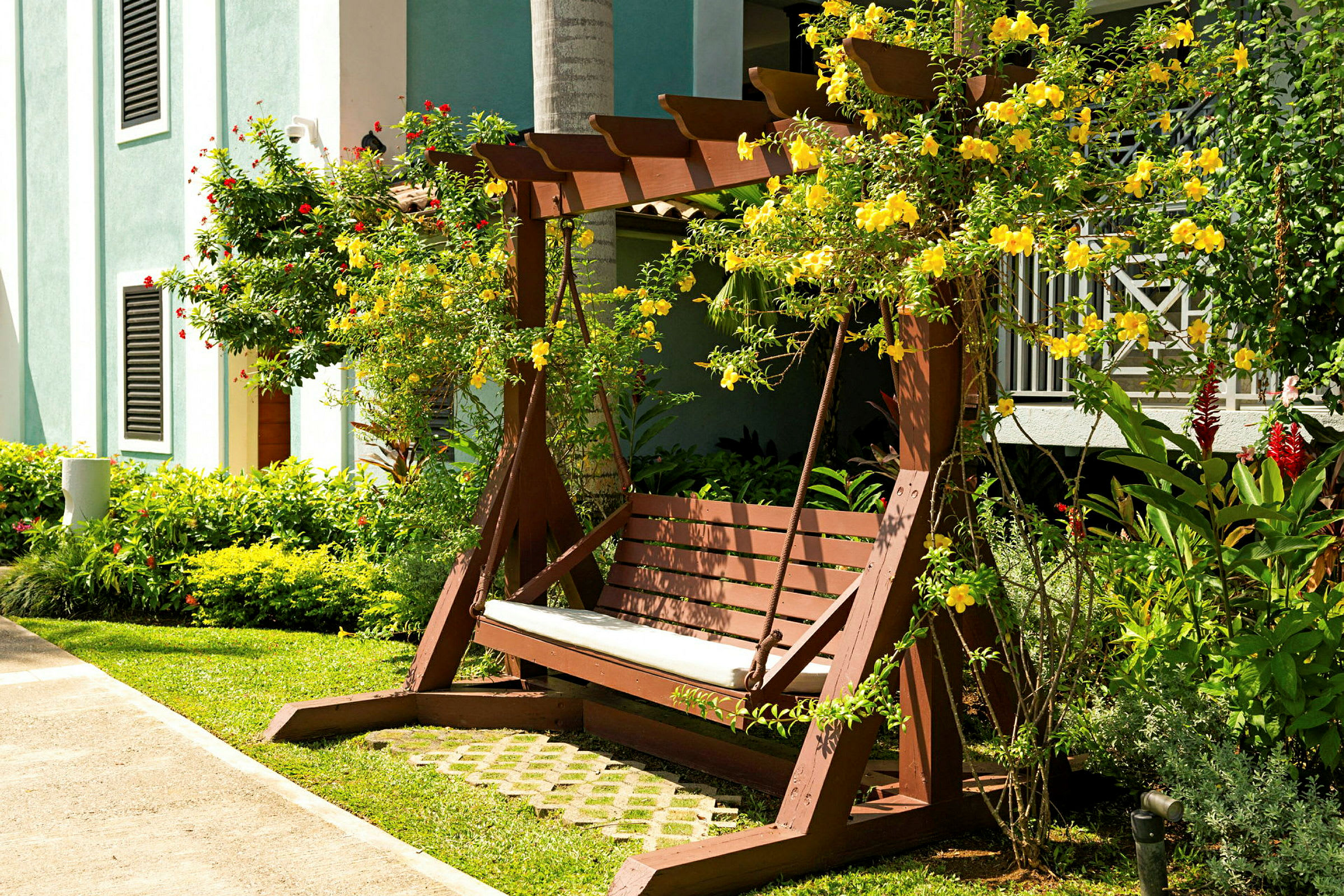 Trebenk med en pergola omgitt av gule blomster og grøntarealer. (AI-generert tekst)