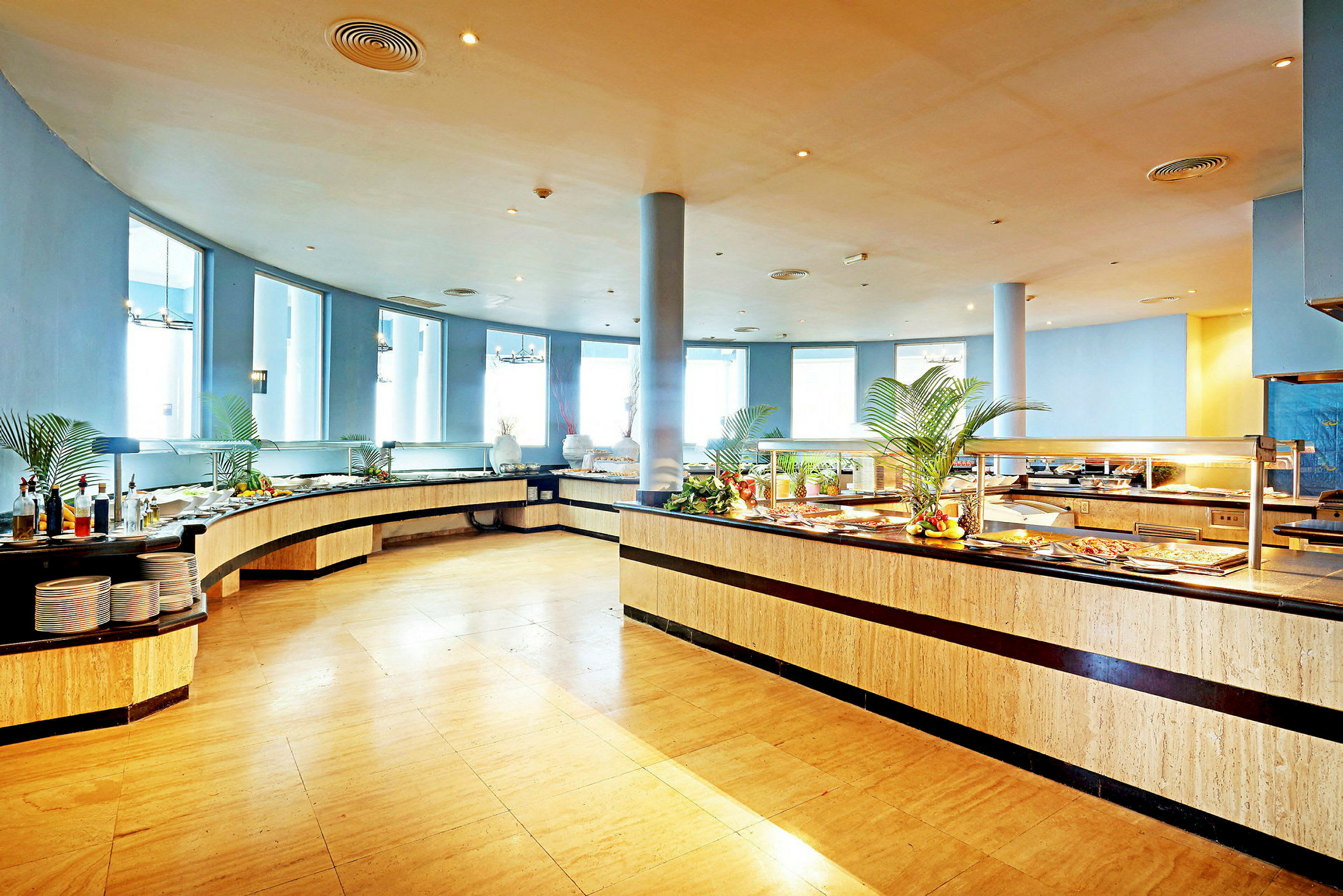 En lys og romslig bufférestaurant med mat plassert på lange serveringsbord. (AI-generert tekst)