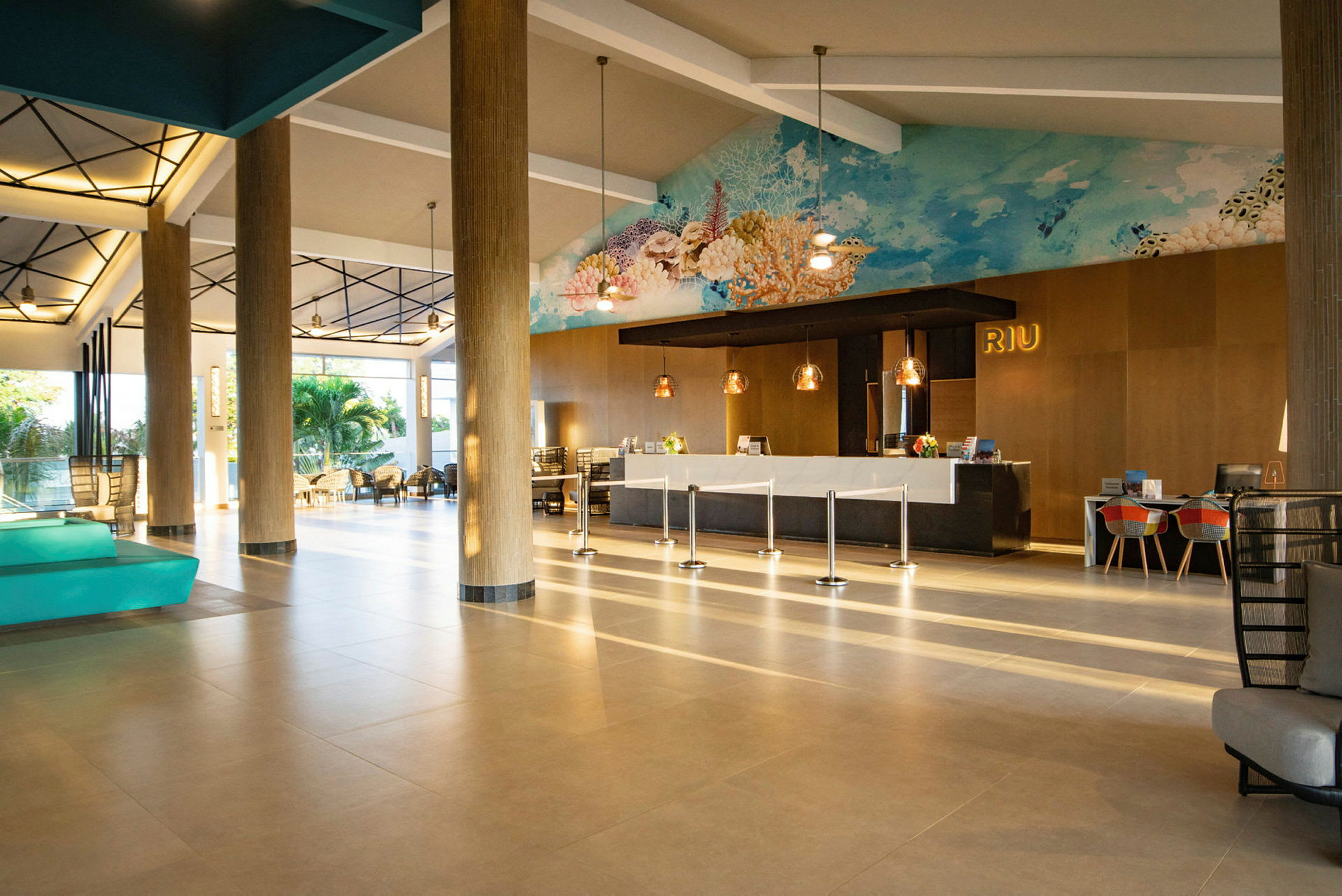Bilde av en hotellobby med lyse gulv, resepsjonsdisk, sitteplasser og kunstverk på veggen. (AI-generert tekst)