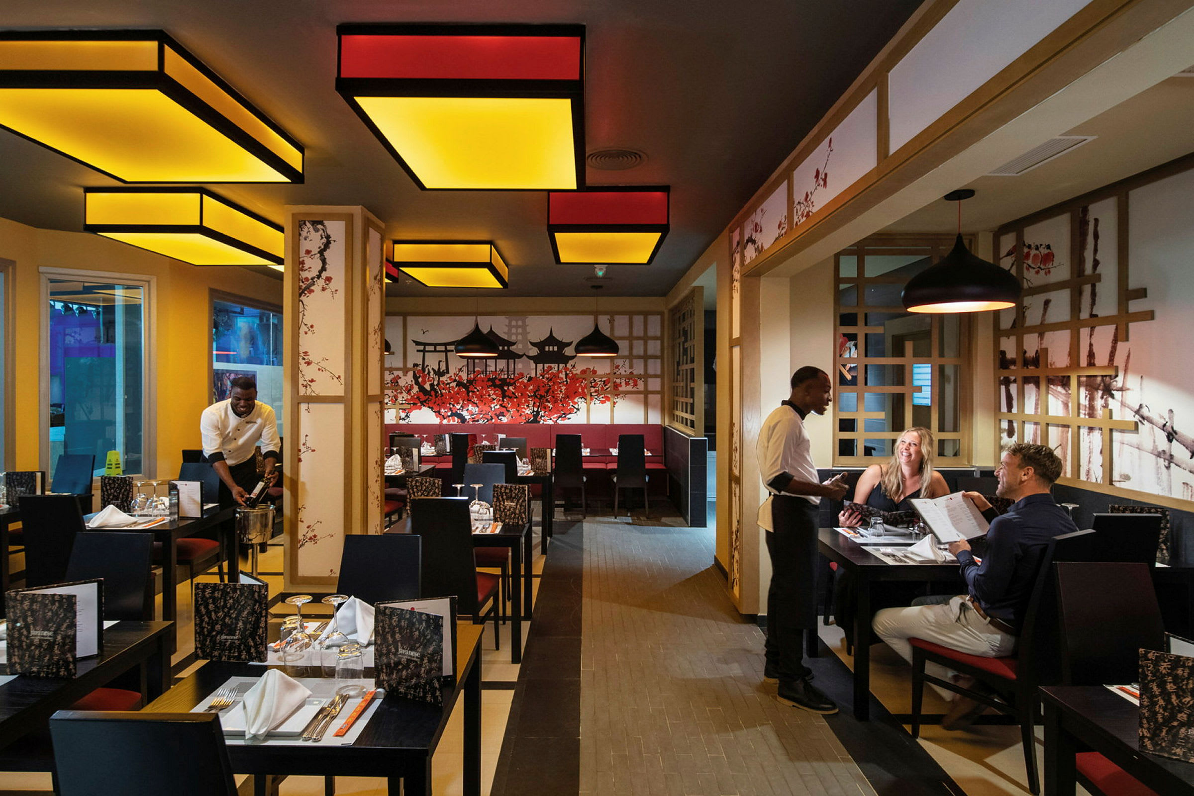 En restaurant med dekorasjoner inspirert av asiatisk kultur og personale som serverer gjester. (AI-generert tekst)