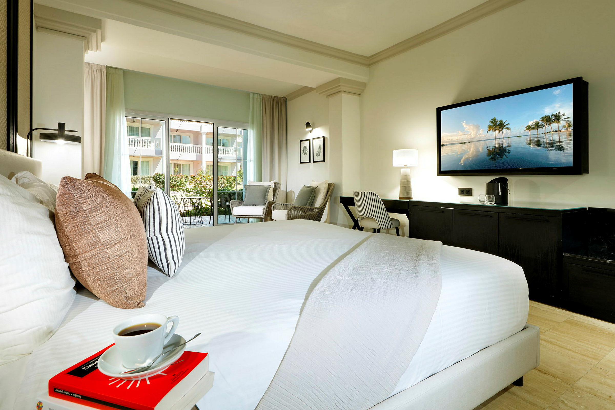 Hotellrom med stor seng, sittegruppe, skrivebord og TV på veggen. (AI-generert tekst)