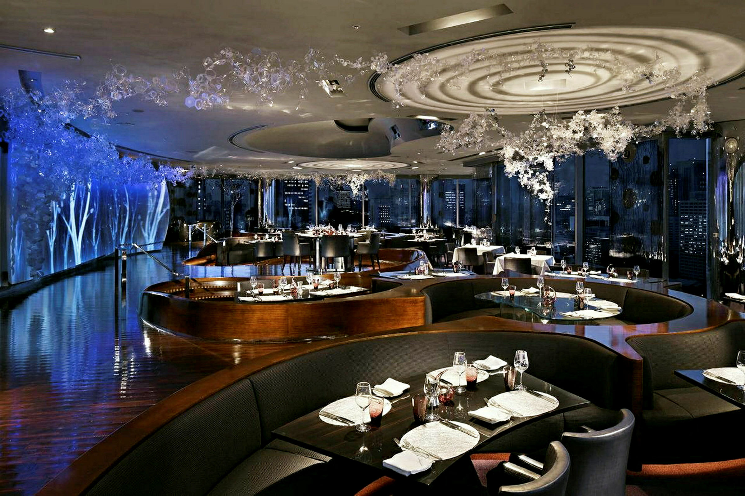 En elegant restaurant med stilfullt interiør, hvor bordene er pent dekket og omgitt av mørke sitteplasser. (AI-generert tekst)