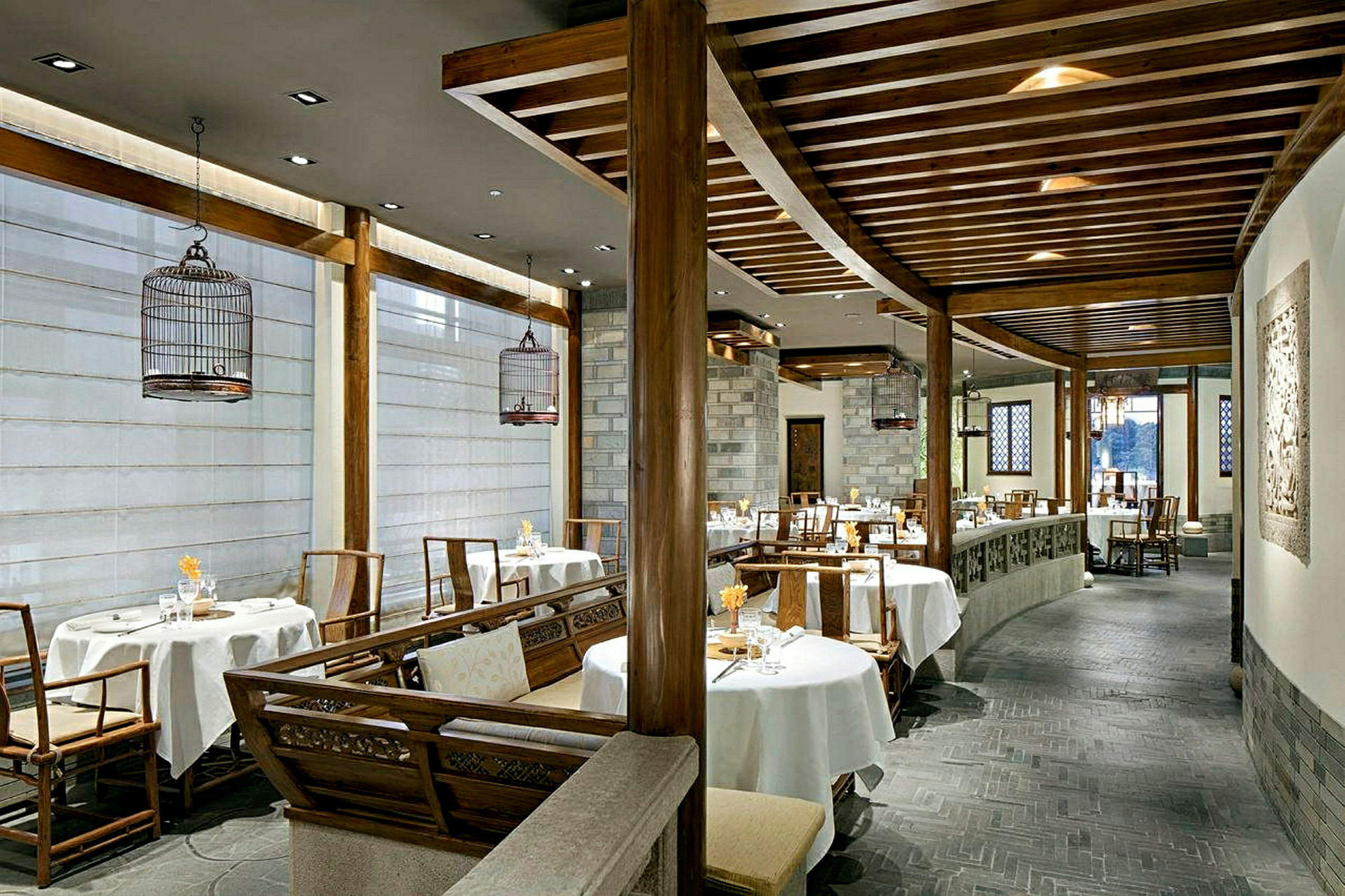 En elegant innredet restaurant med runde bord og stoler, hvite duker og innslag av tre i interiøret. (AI-generert tekst)