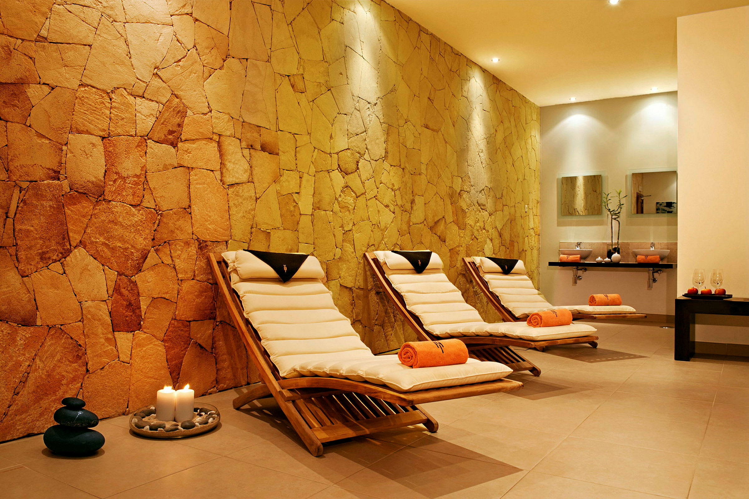 Spa-rom med tre solsenger og en vegg av naturstein. (AI-generert tekst)