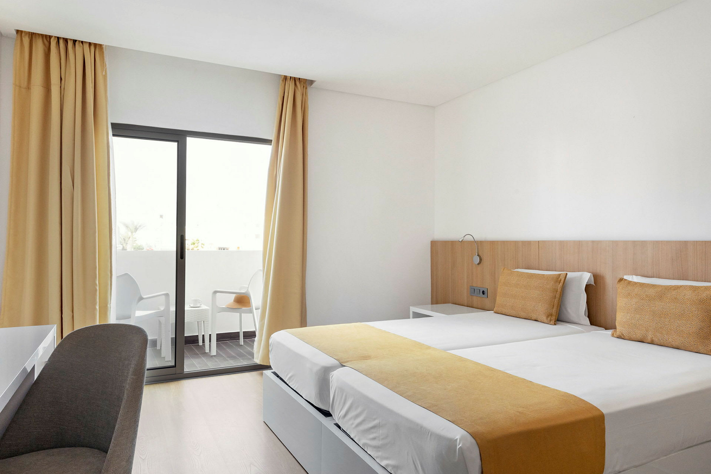 Hotellrom med to enkeltsenger og balkong. (AI-generert tekst)