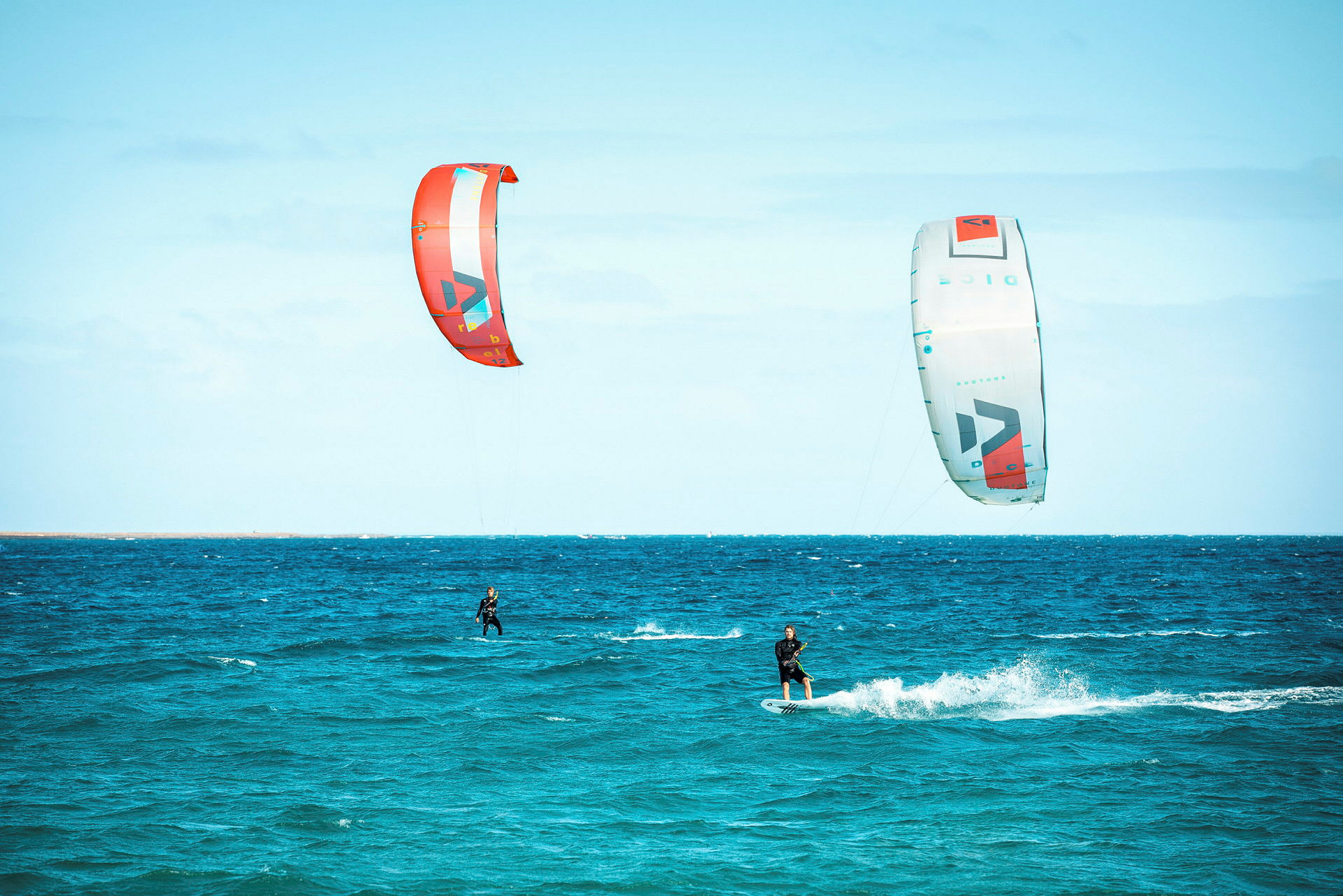 To personer kitesurfer på havet med fargerike drager. (AI-generert tekst)