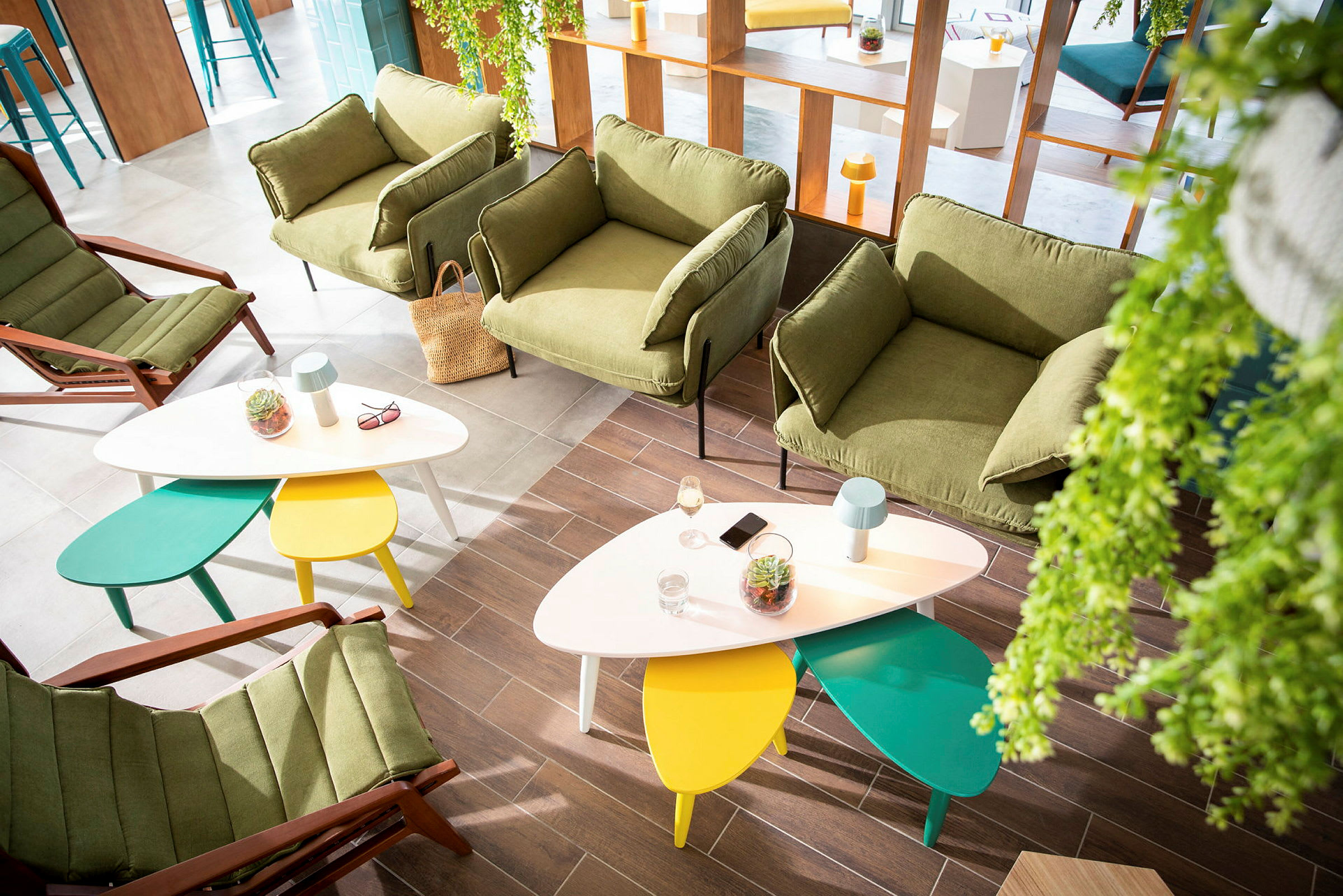 Moderne lounge med grønne lenestoler og fargerike bord. (AI-generert tekst)