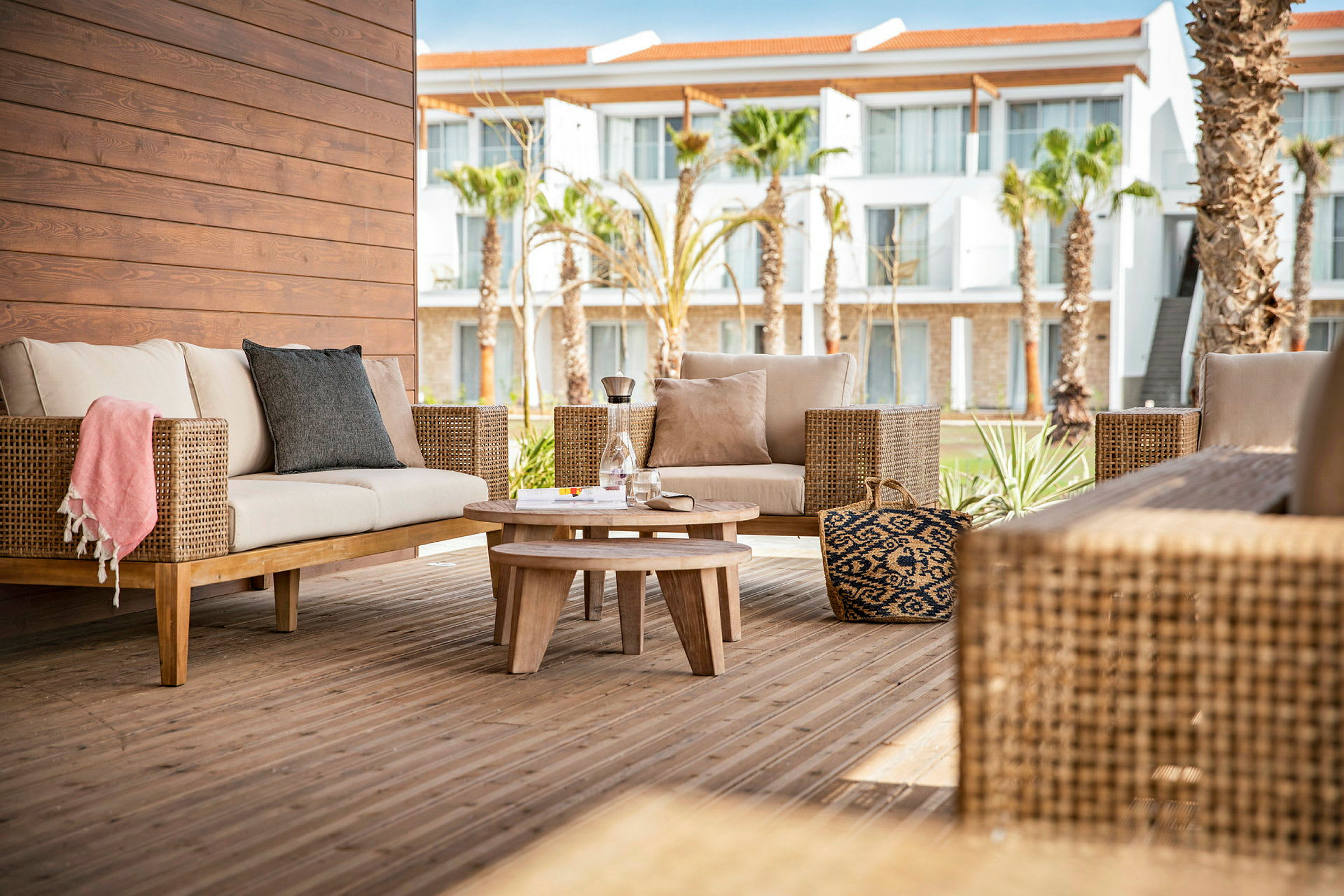 Utendørs loungeområde med rottingmøbler og et trebord på en terrasse. (AI-generert tekst)