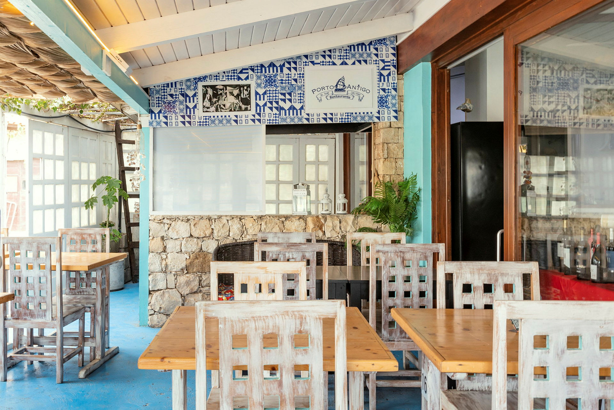 Restaurant med trebord og stoler samt dekorert vegg med blå fliser. (AI-generert tekst)