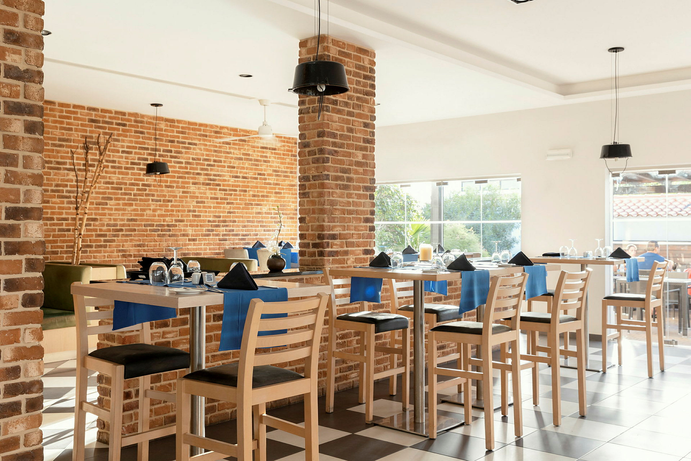 Interiør av en restaurant med murvegger, fullt møblert med bord og stoler dekorert med blå detaljer. (AI-generert tekst)