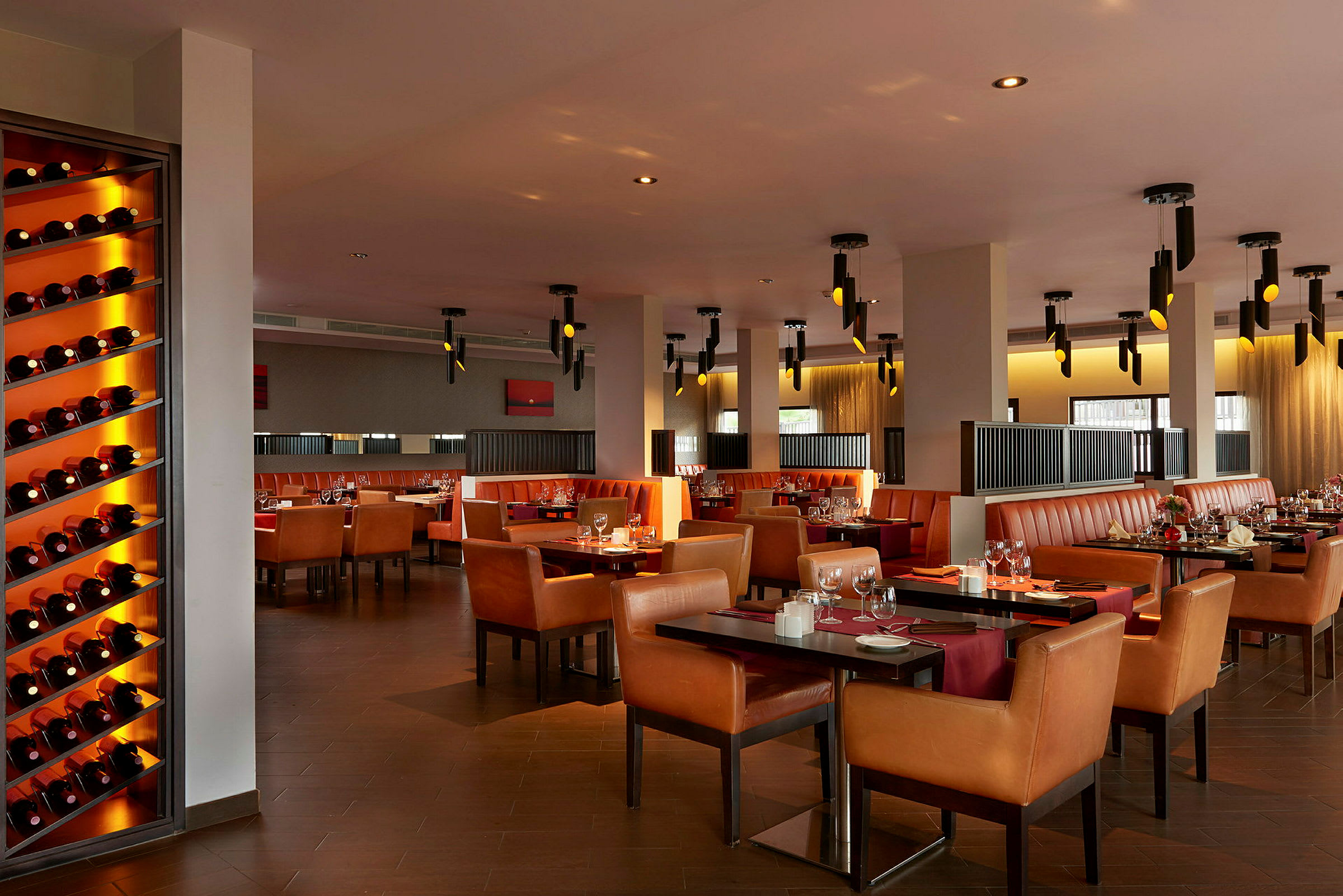 En restaurant med flere bord, stoler og vinflasker på en hylle. (AI-generert tekst)