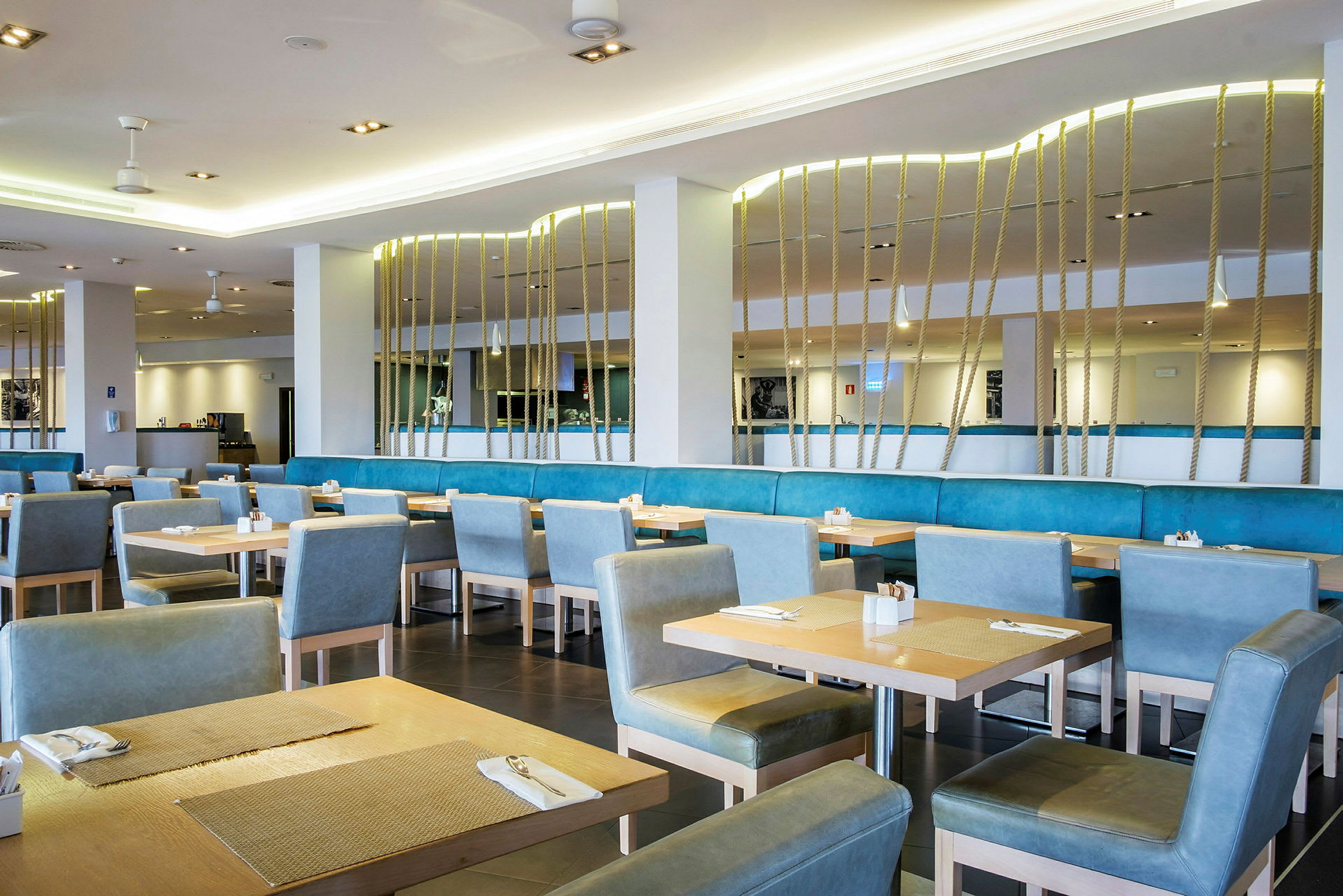 Interiør av en restaurant med bord og blå stoler. (AI-generert tekst)