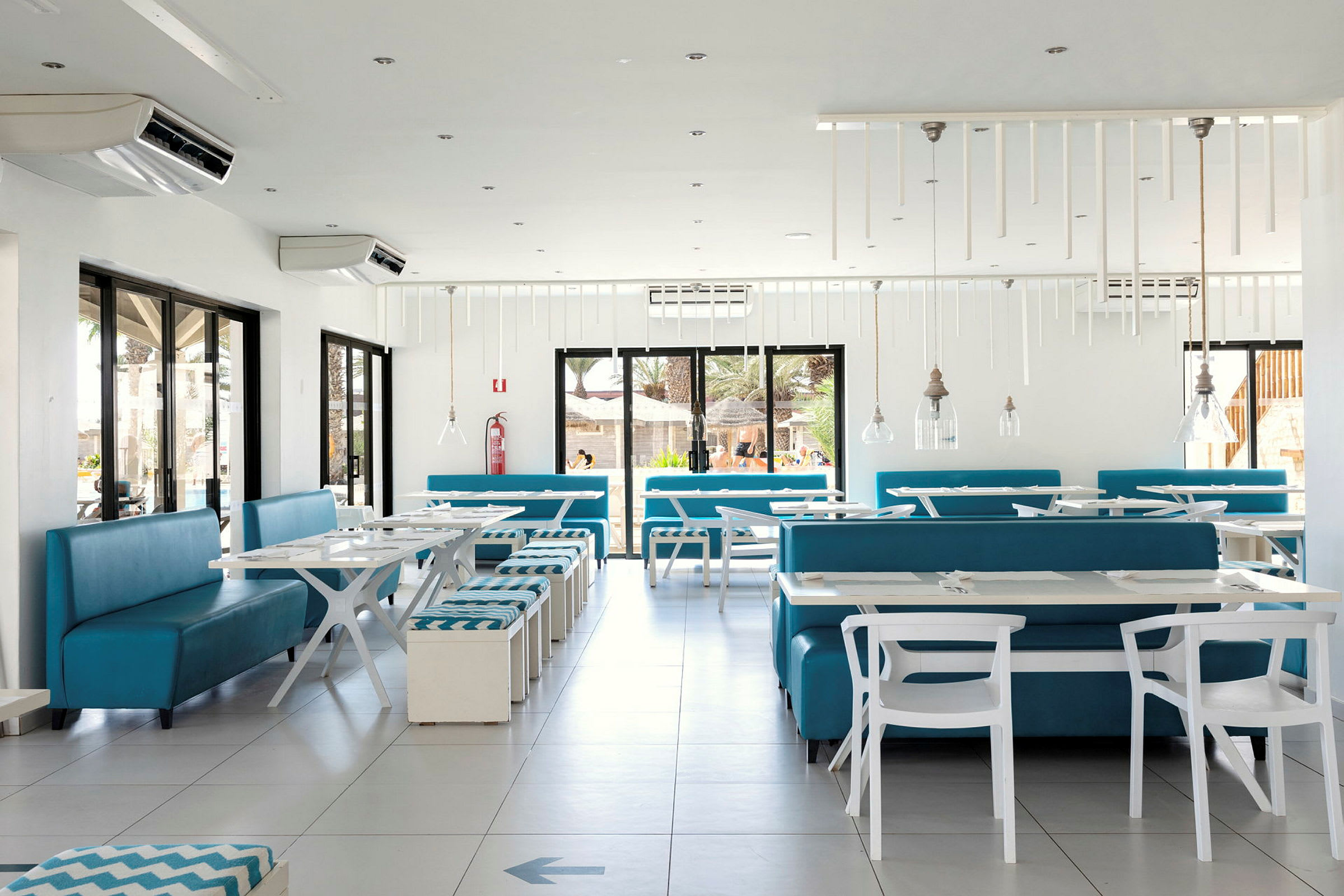 Lys og moderne restaurant med hvite bord og blå sittemøbler. (AI-generert tekst)