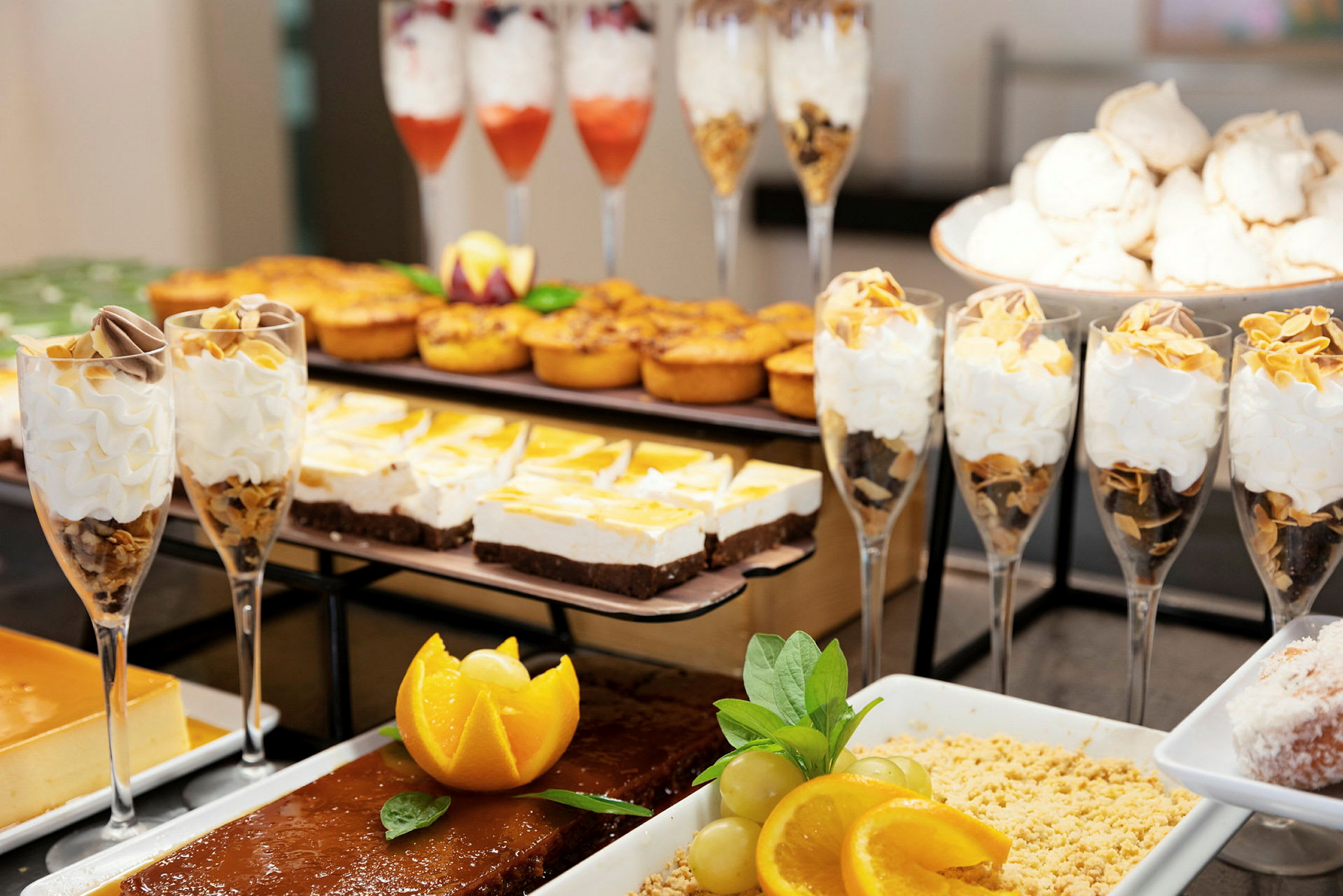 Bilde av et dessertbord med ulike søtsaker, inkludert glass med krem, kaker og frukt. (AI-generert tekst)