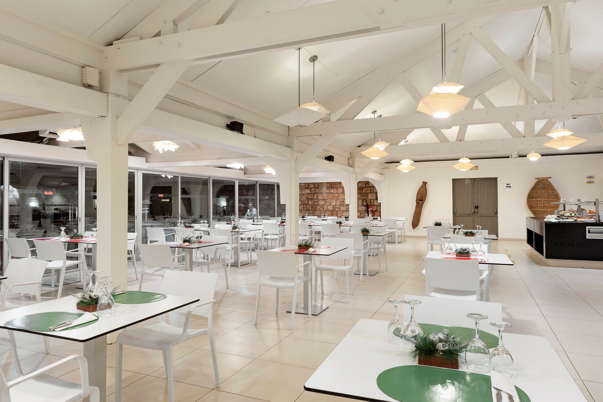 Et lyst restaurantområde med hvite bord og stoler og moderne hengende lamper. (AI-generert tekst)