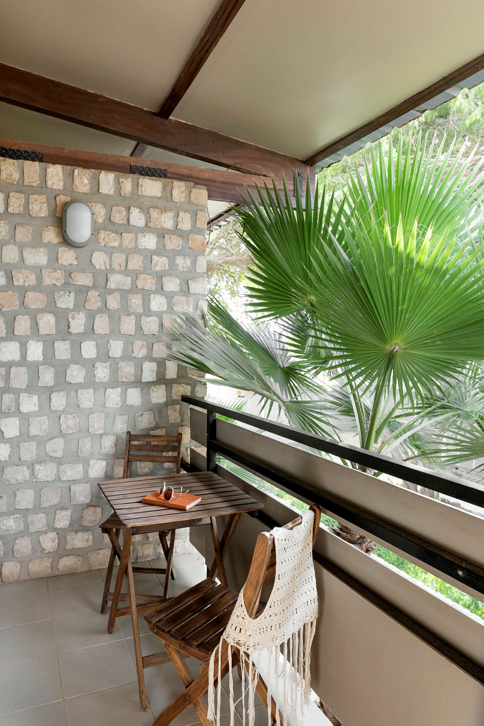 Et bord og to stoler på en terrasse med utsikt over en palme. (AI-generert tekst)