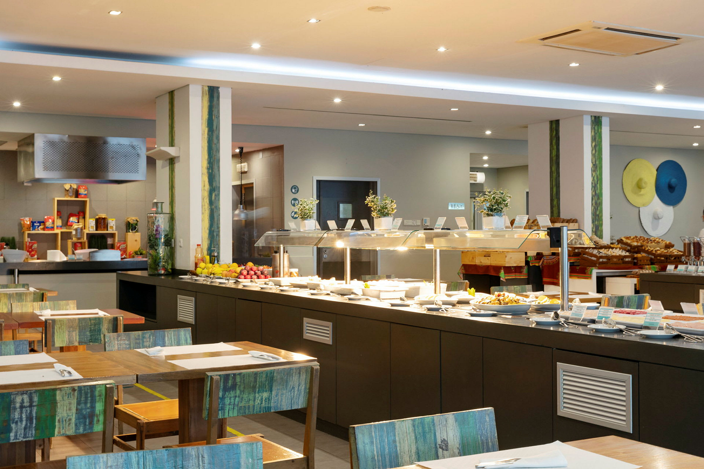 Interiør av en bufférestaurant med serveringsbord fylt med ulike retter og frukter. (AI-generert tekst)