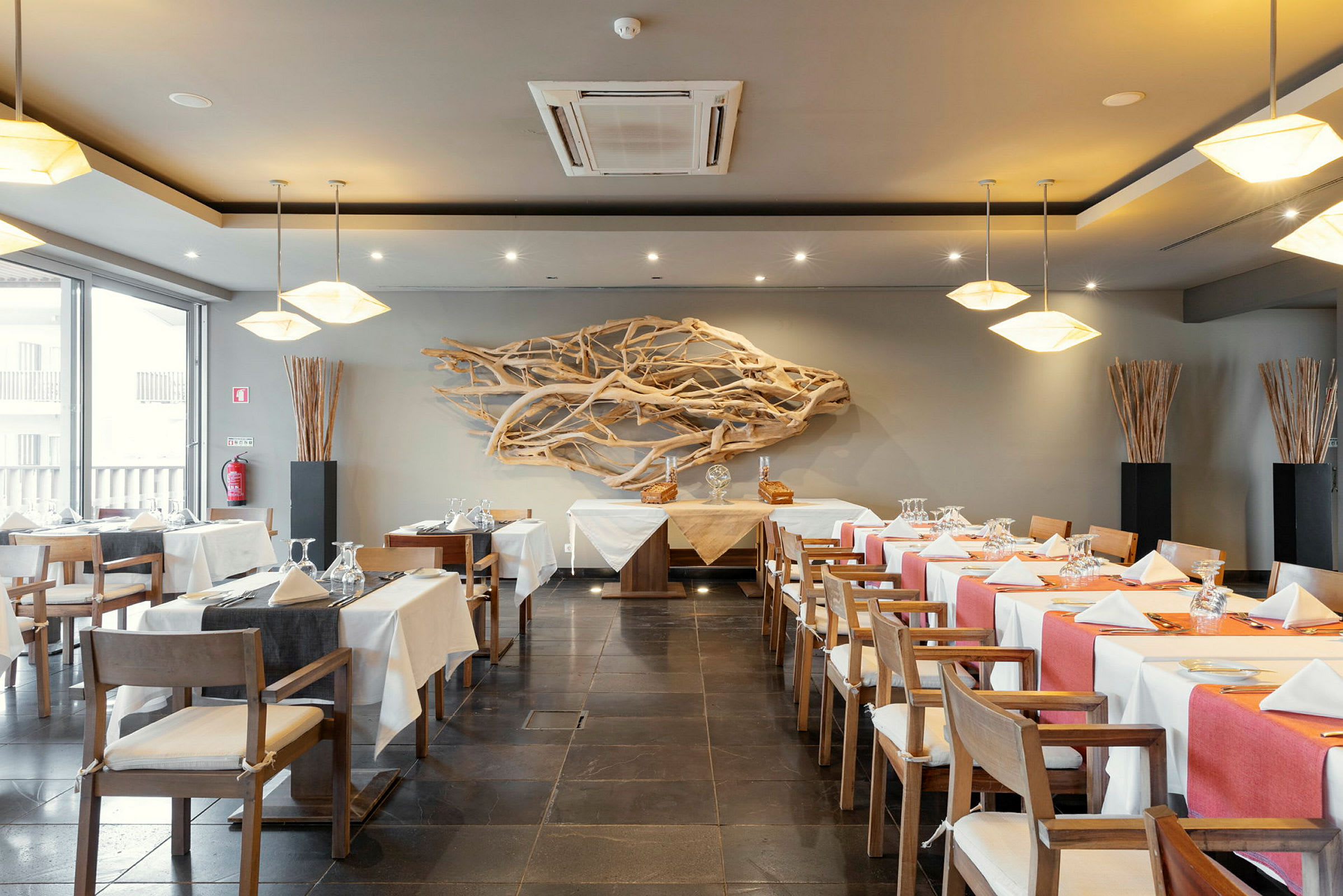 En restaurant med dekkede bord, dekorerte stoler og trekunst på veggen. (AI-generert tekst)