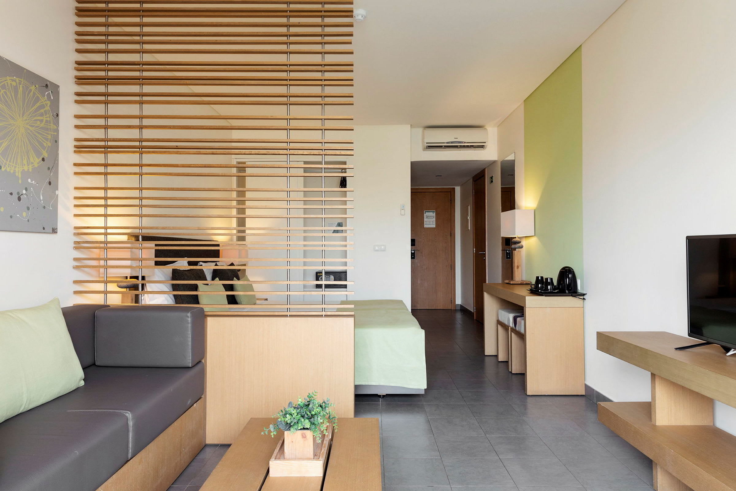 Moderne hotellrom med sitteområde, seng og møbler i naturfarger. (AI-generert tekst)