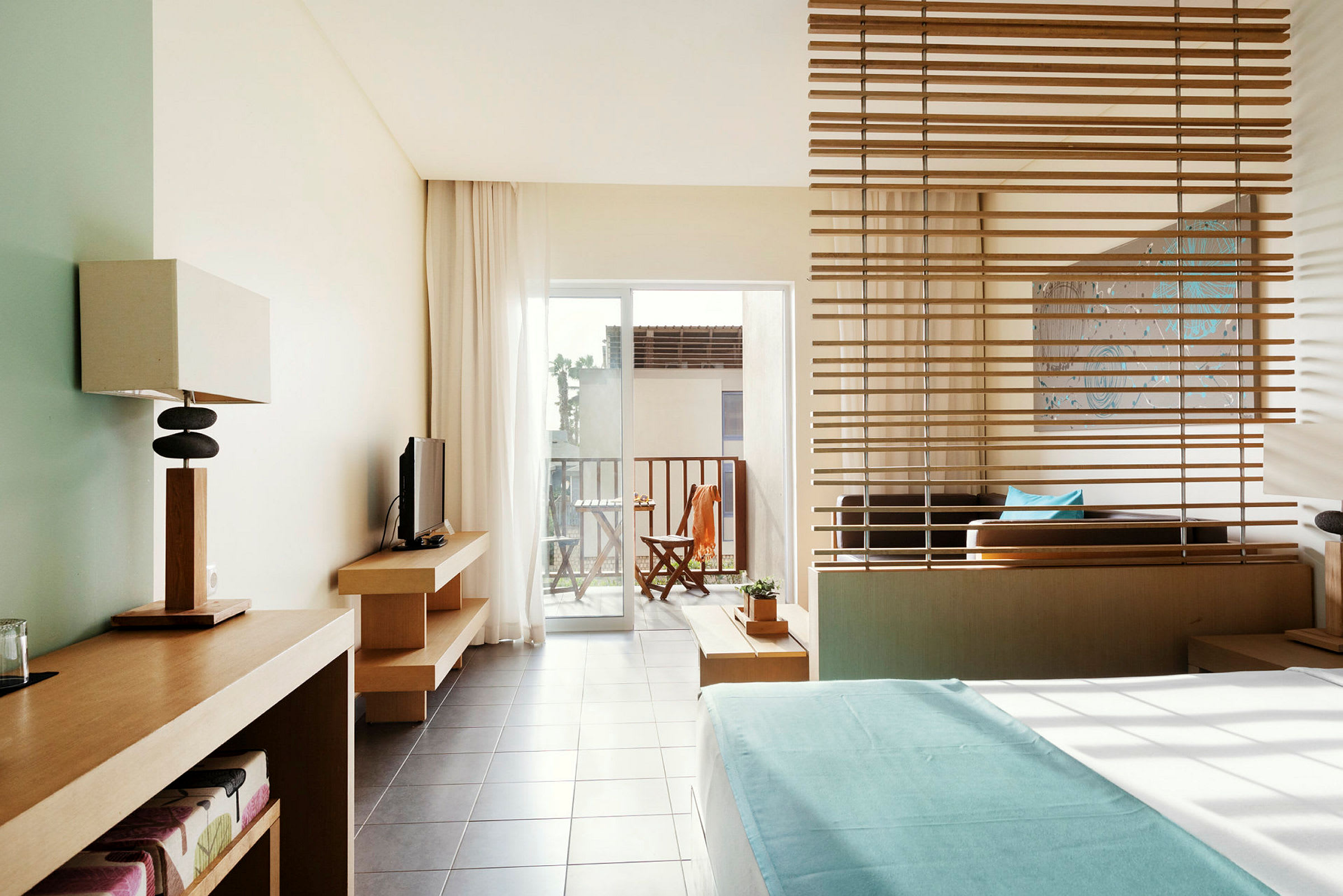 Et hotellrom med moderne interiør og utsikt mot en balkong med utemøbler. (AI-generert tekst)