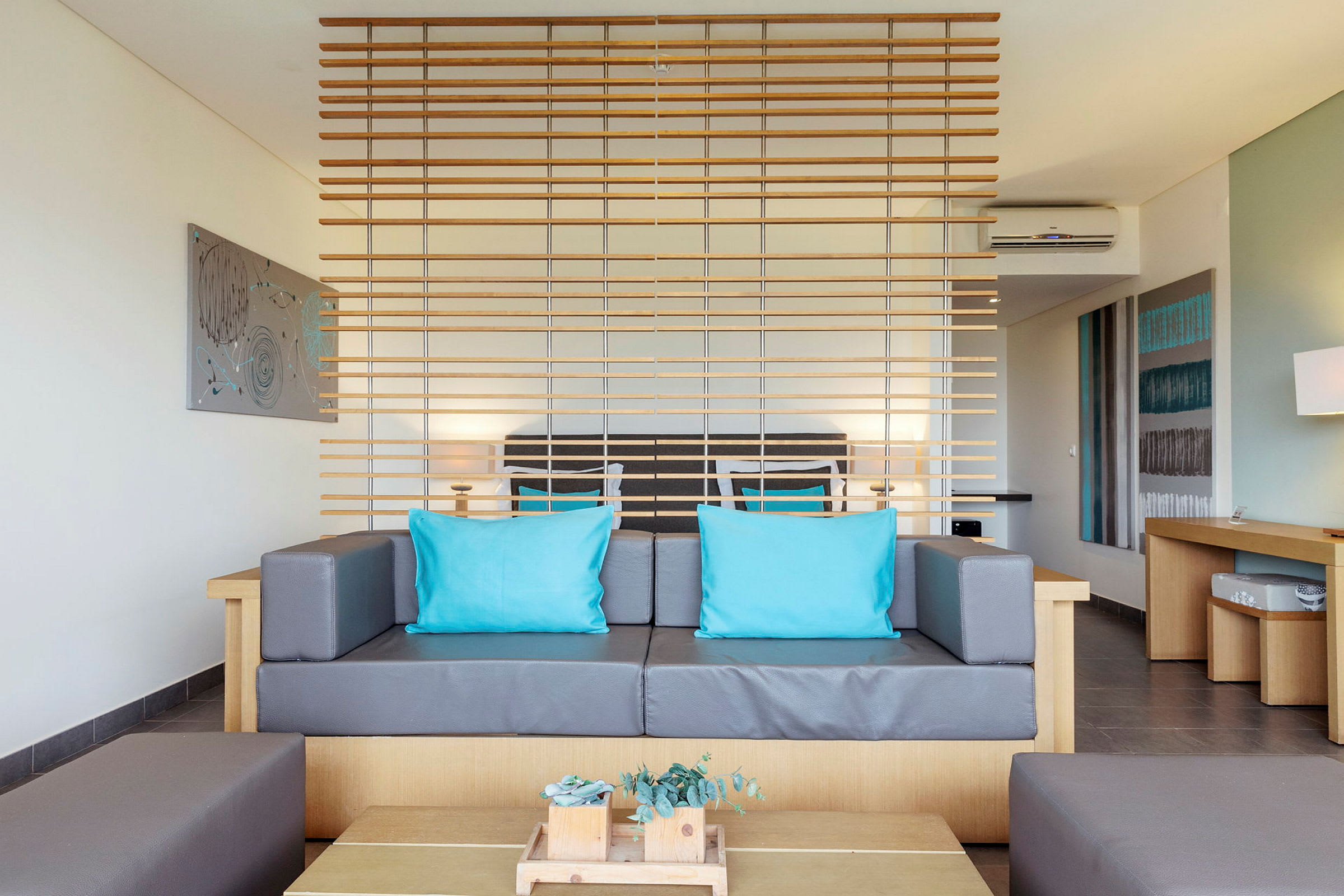 Moderne innredet rom med sofa, turkise puter og trepanel som skillevegg. (AI-generert tekst)