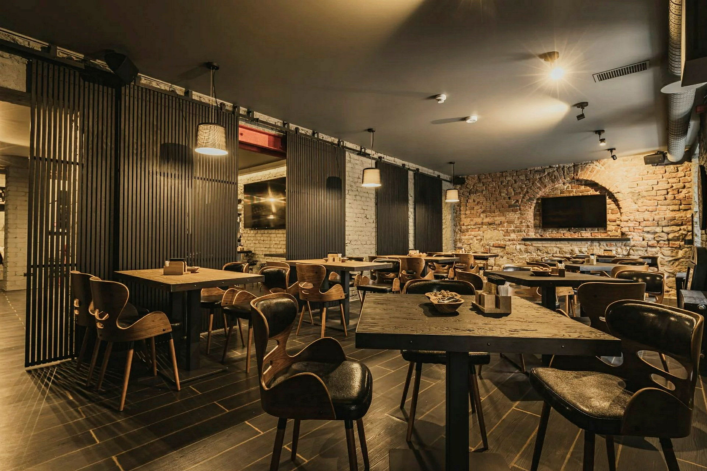 En restaurant med trebord og stoler samt murvegger. (AI-generert tekst)