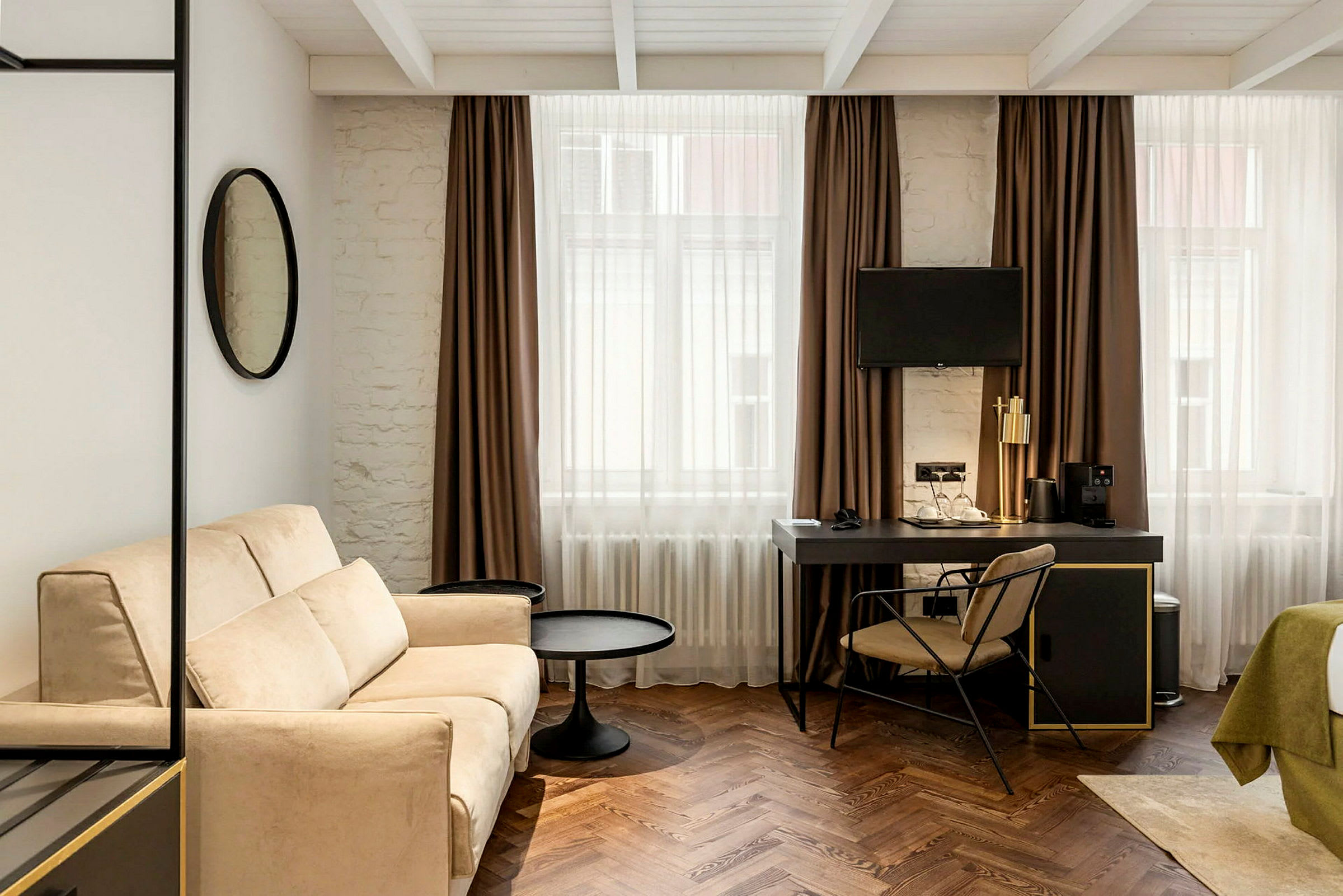 Moderne møblert hotellrom med sofa, skrivebord og TV. (AI-generert tekst)