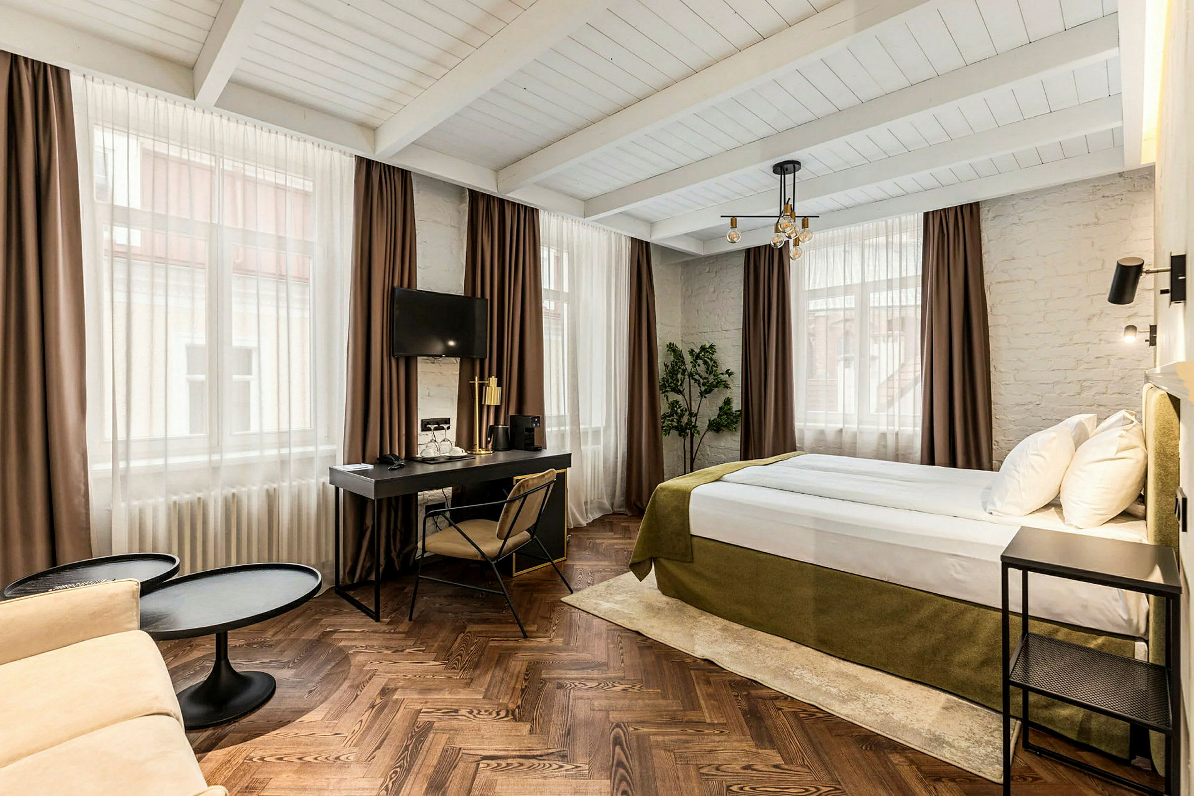 Hotellrom med seng, skrivebord og sittegruppe. (AI-generert tekst)