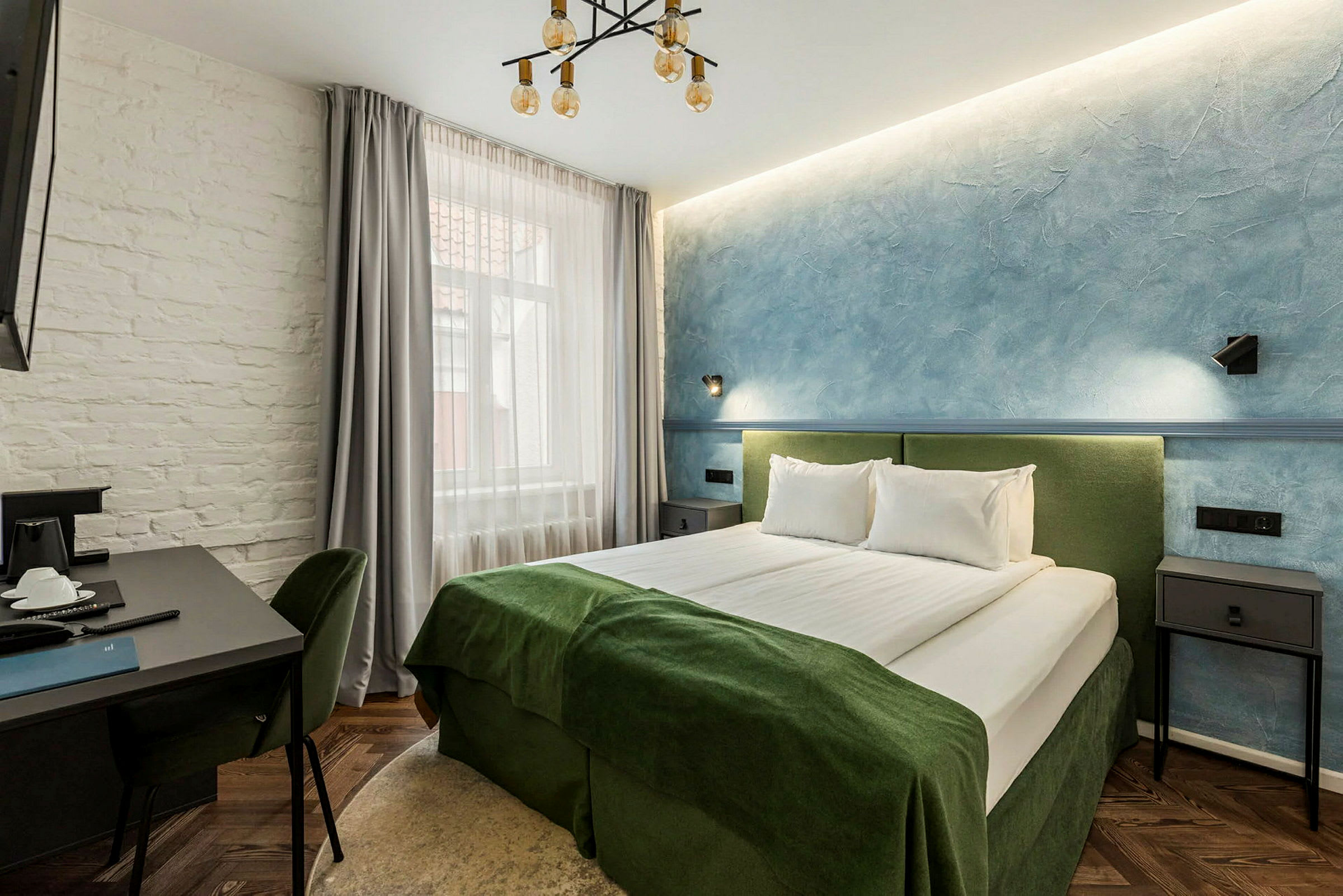 Et hotellrom med en dobbeltseng, bord og stoler. (AI-generert tekst)