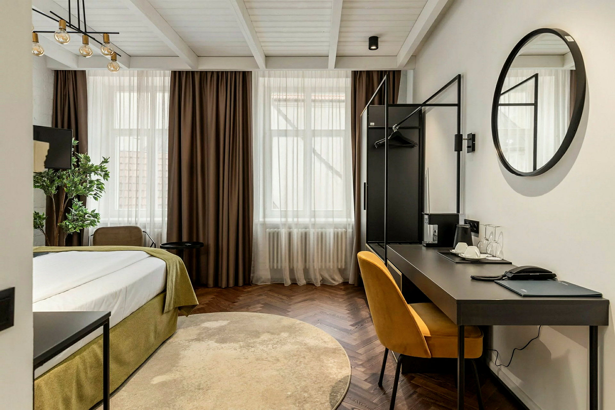 Et moderne hotellrom med en seng, skrivebord og en gul stol. (AI-generert tekst)
