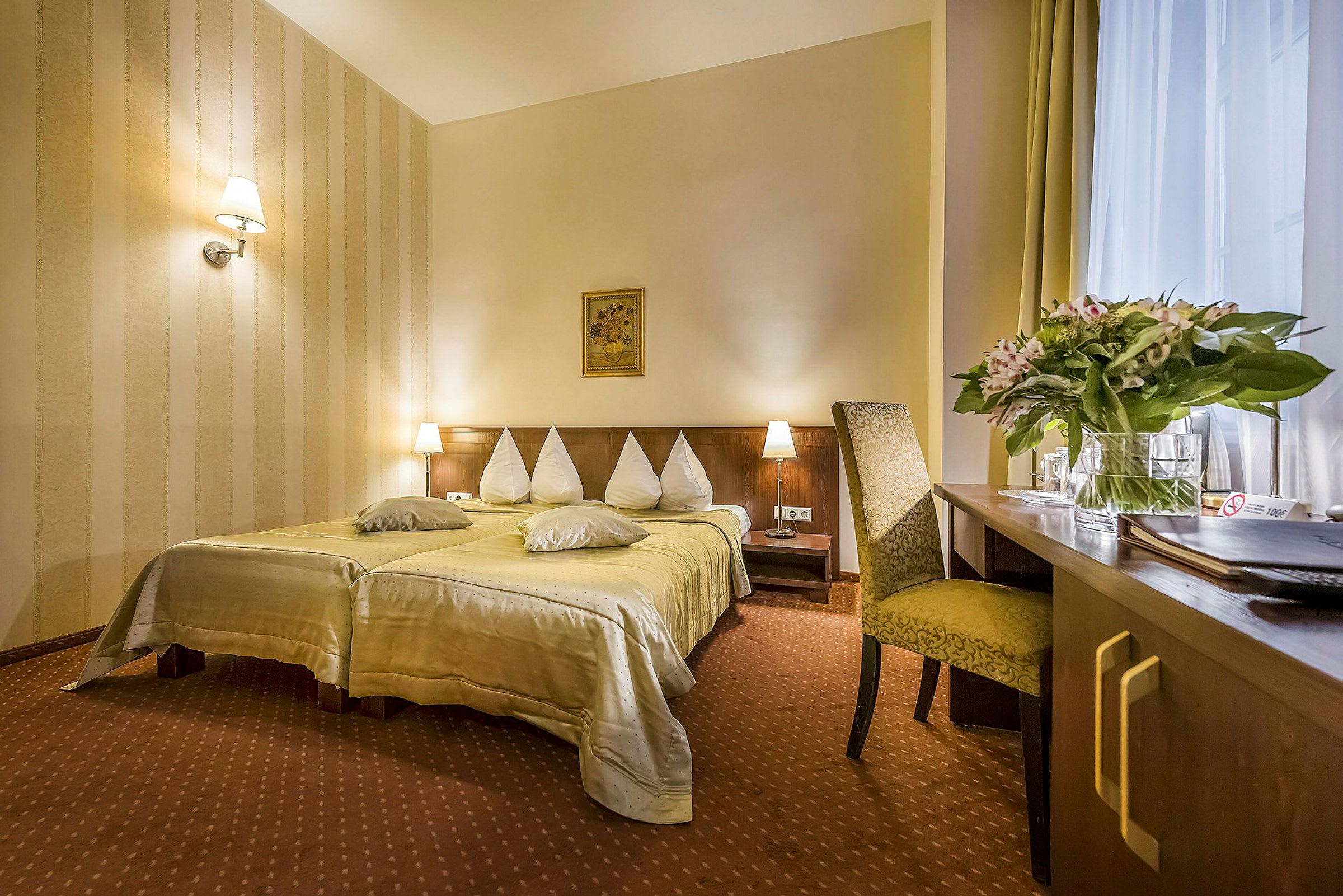 Hotellrom med en dobbeltseng, nattbord og en skrivebordsdel med stol. (AI-generert tekst)
