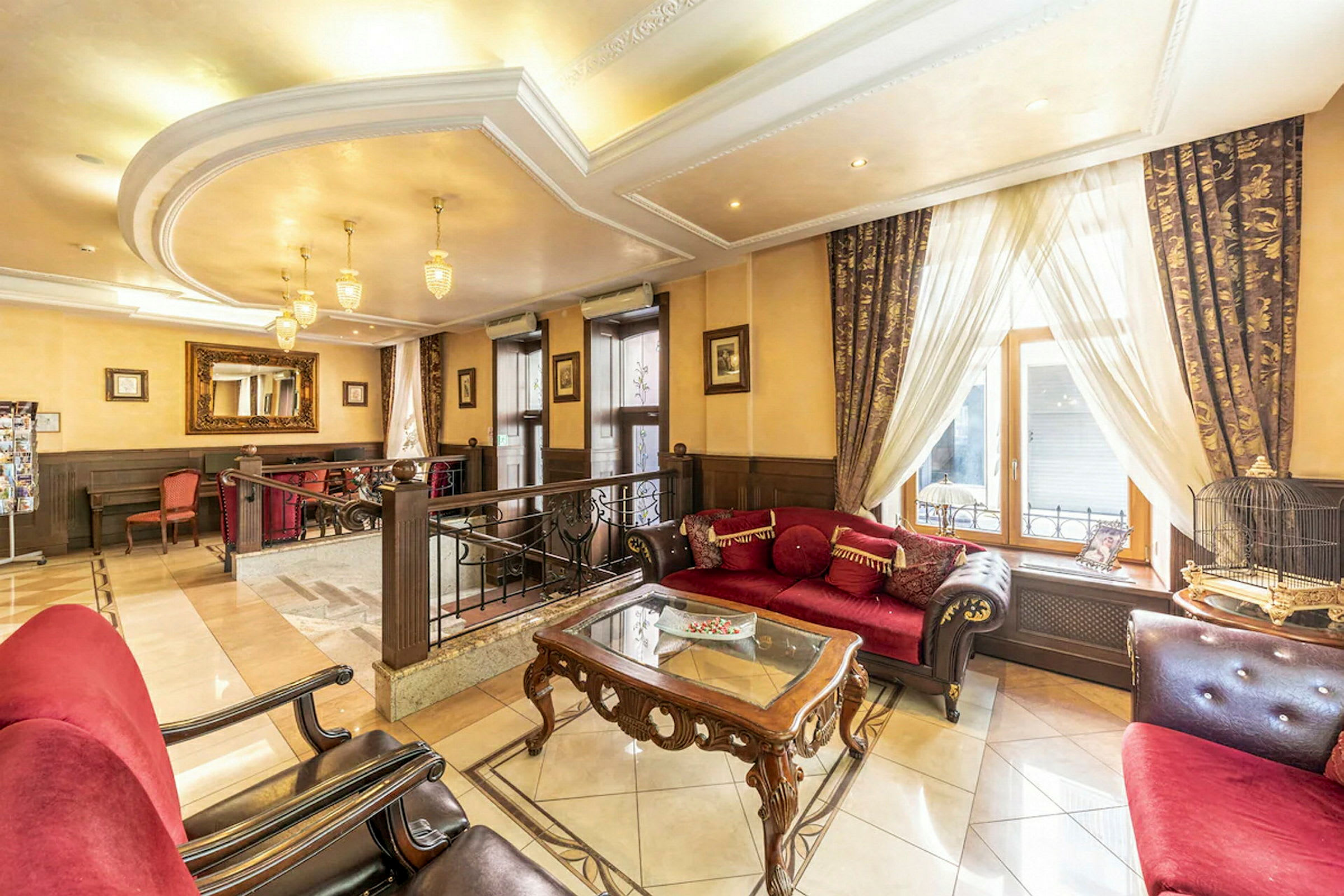 Lys og elegant hotellobby med røde sofaer og klassisk innredning. (AI-generert tekst)
