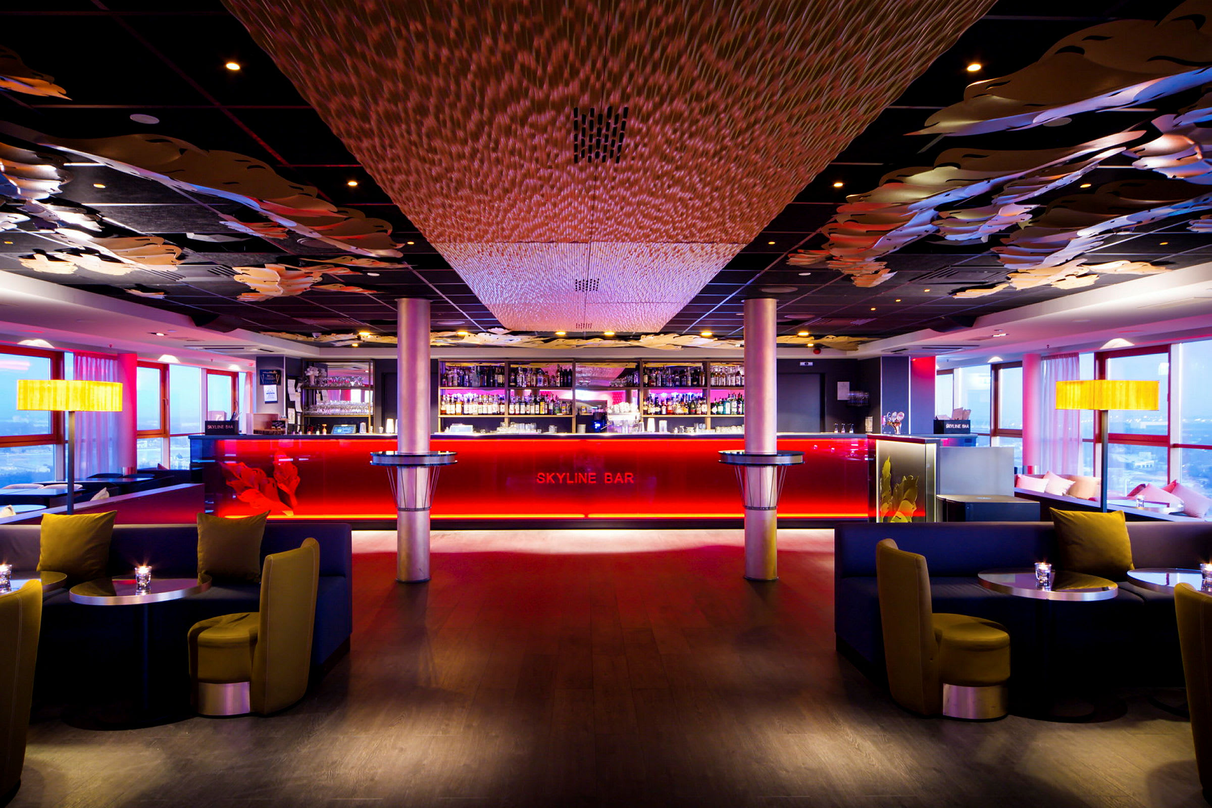 En elegant bar med rød belysning, mørke møbler og dekorert tak. (AI-generert tekst)
