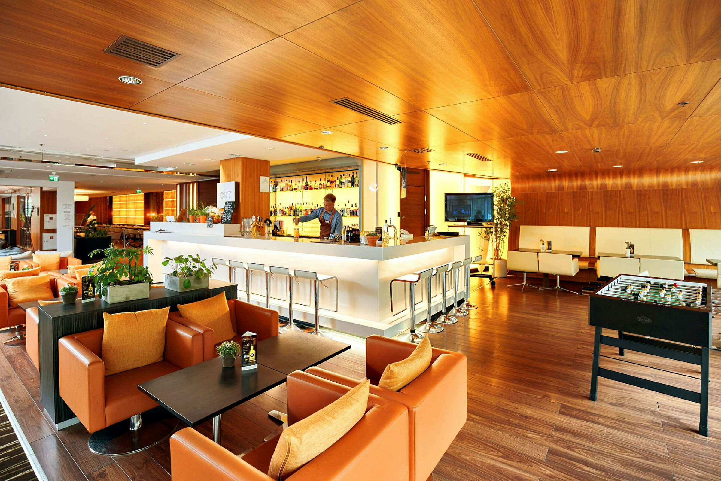 En moderne lounge med en bar, sittegrupper og et fotballspill. (AI-generert tekst)