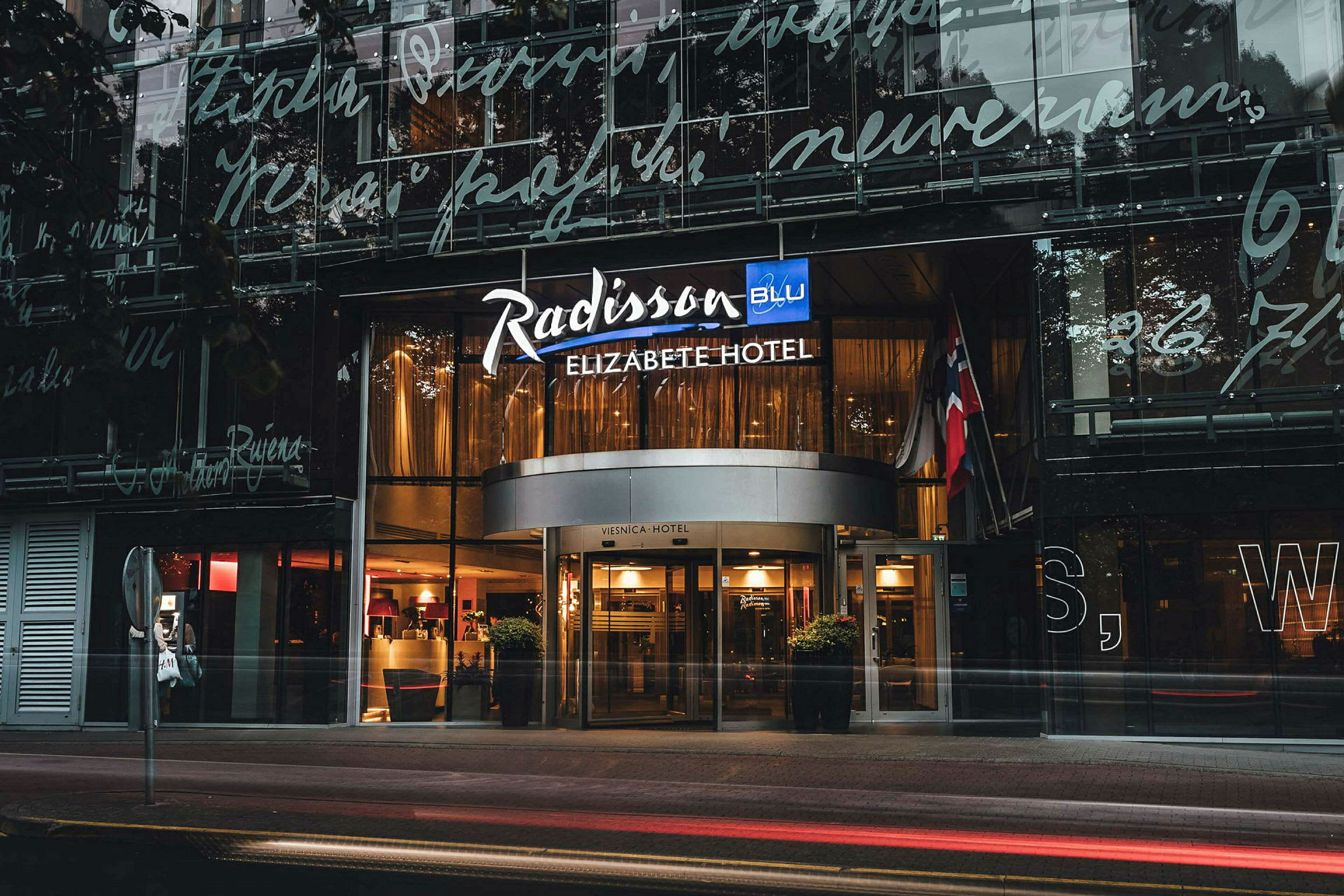 Inngangen til et hotell med skilt hvor det står "Radisson Blu Elizabete Hotel". (AI-generert tekst)