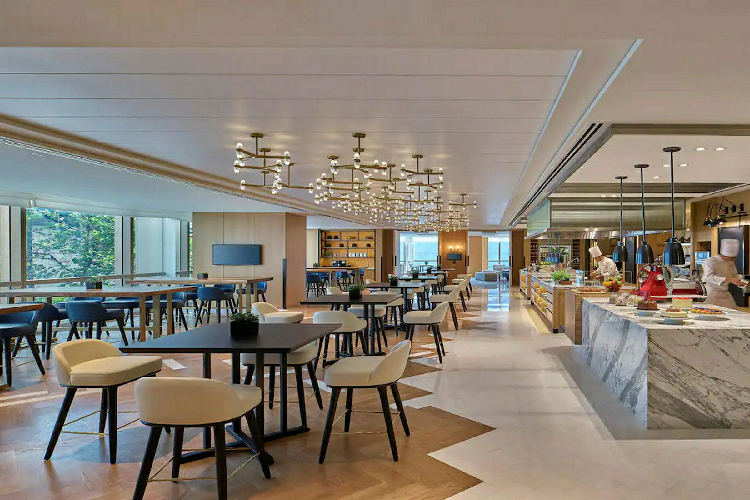 En moderne restaurant med bord, stoler og et kjøkkenområde hvor to personer jobber. (AI-generert tekst)