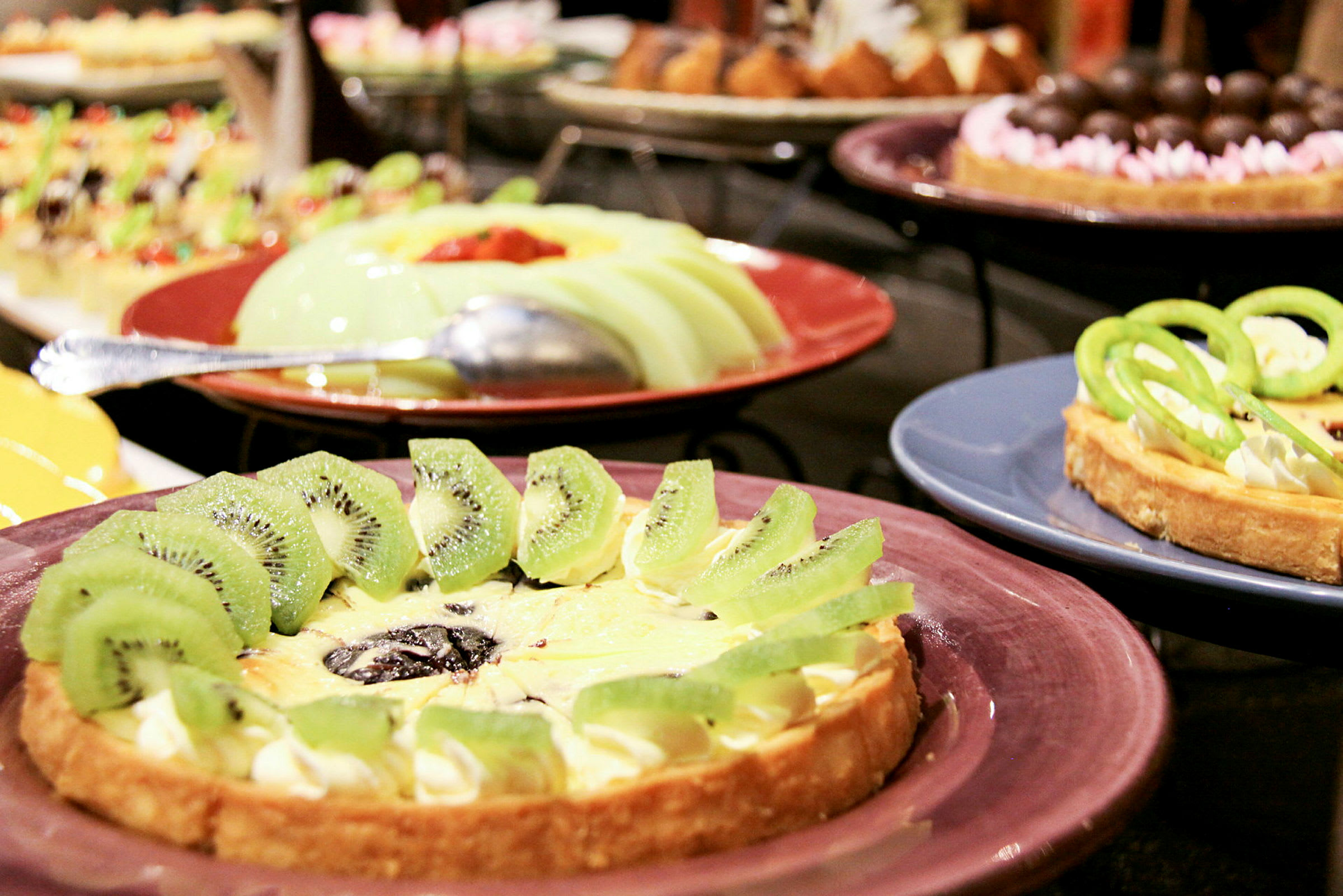 Ulike desserter, inkludert en pai dekorert med kiwi på en tallerken. (AI-generert tekst)