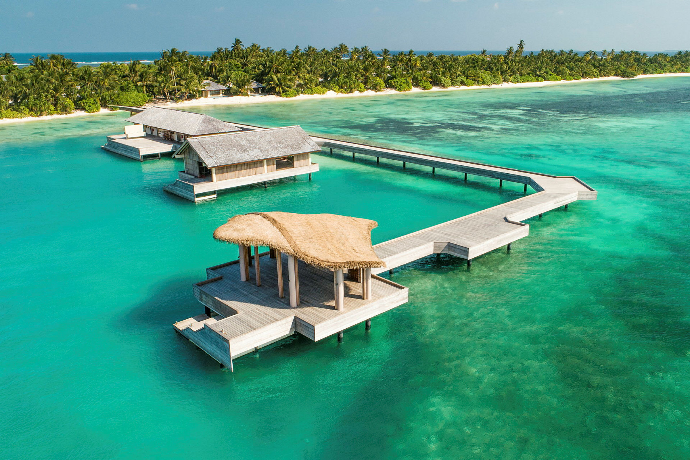 Overvannsbungalower ved en tropisk strand med turkis hav. (AI-generert tekst)