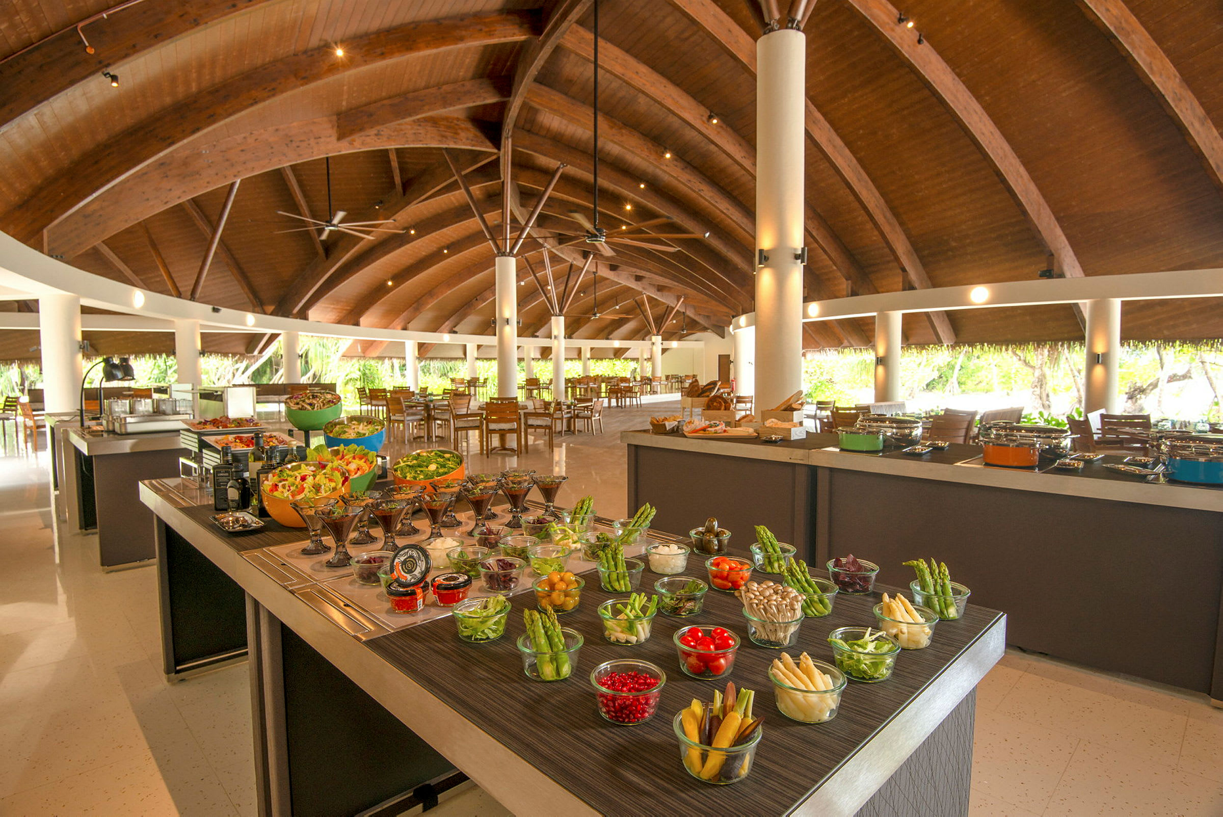 Buffébord med ulike friske grønnsaker og salater i en romslig restaurant med trebjælker. (AI-generert tekst)