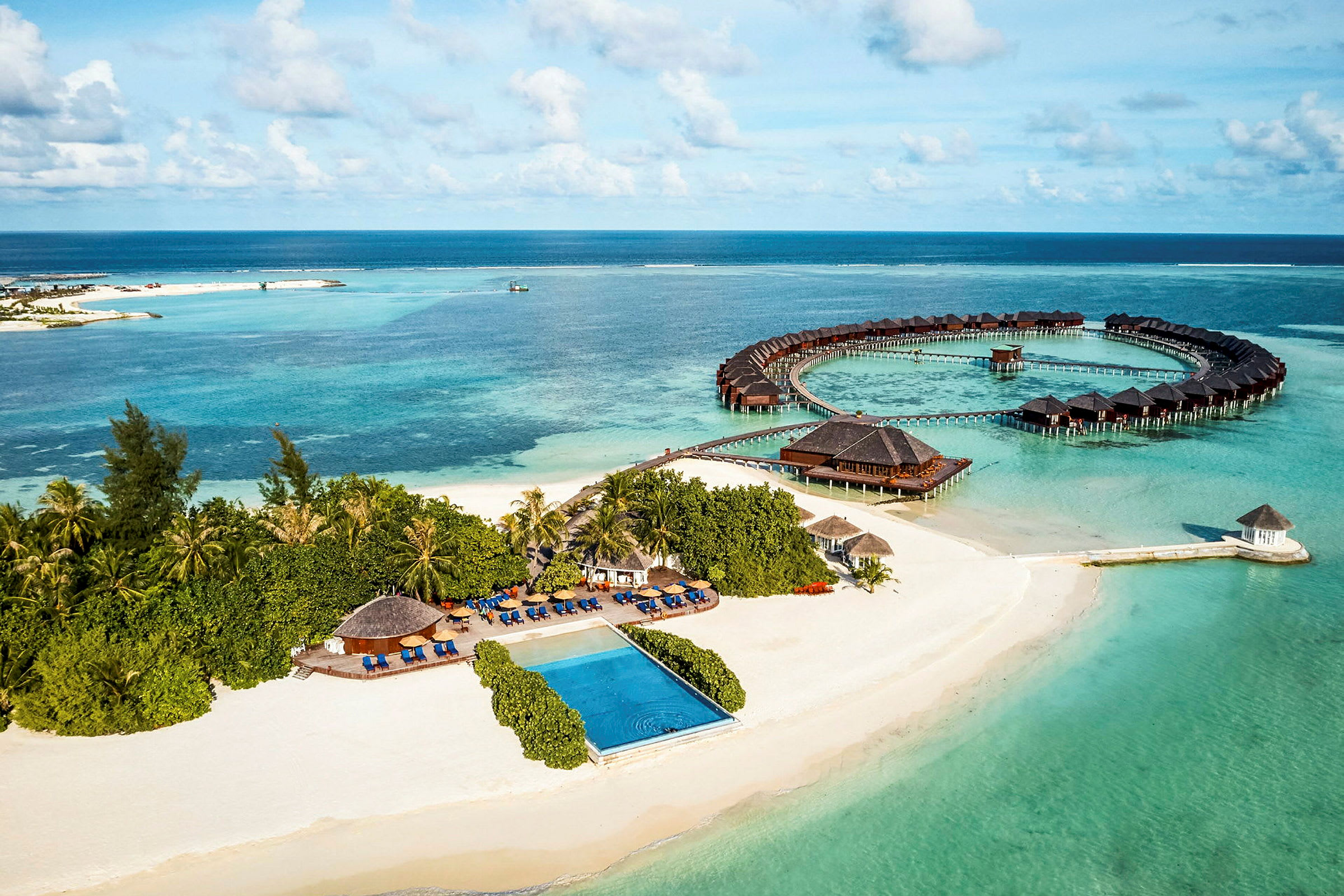 Luftfoto av en tropisk kyst med sandstrand, hav og overnattingsbungalower. (AI-generert tekst)
