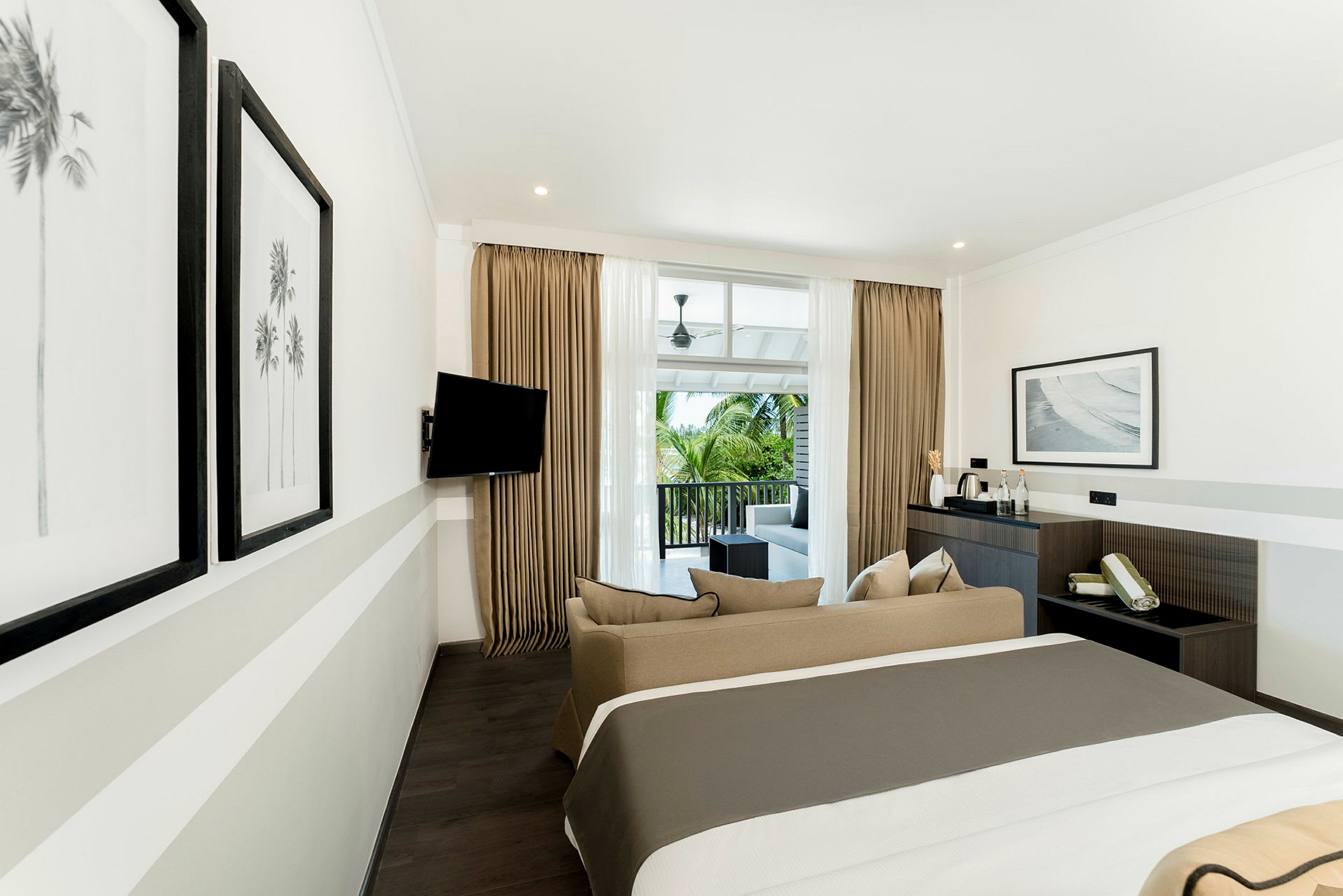 Et moderne hotellrom med en dobbeltseng, sofa og balkong med utsikt. (AI-generert tekst)