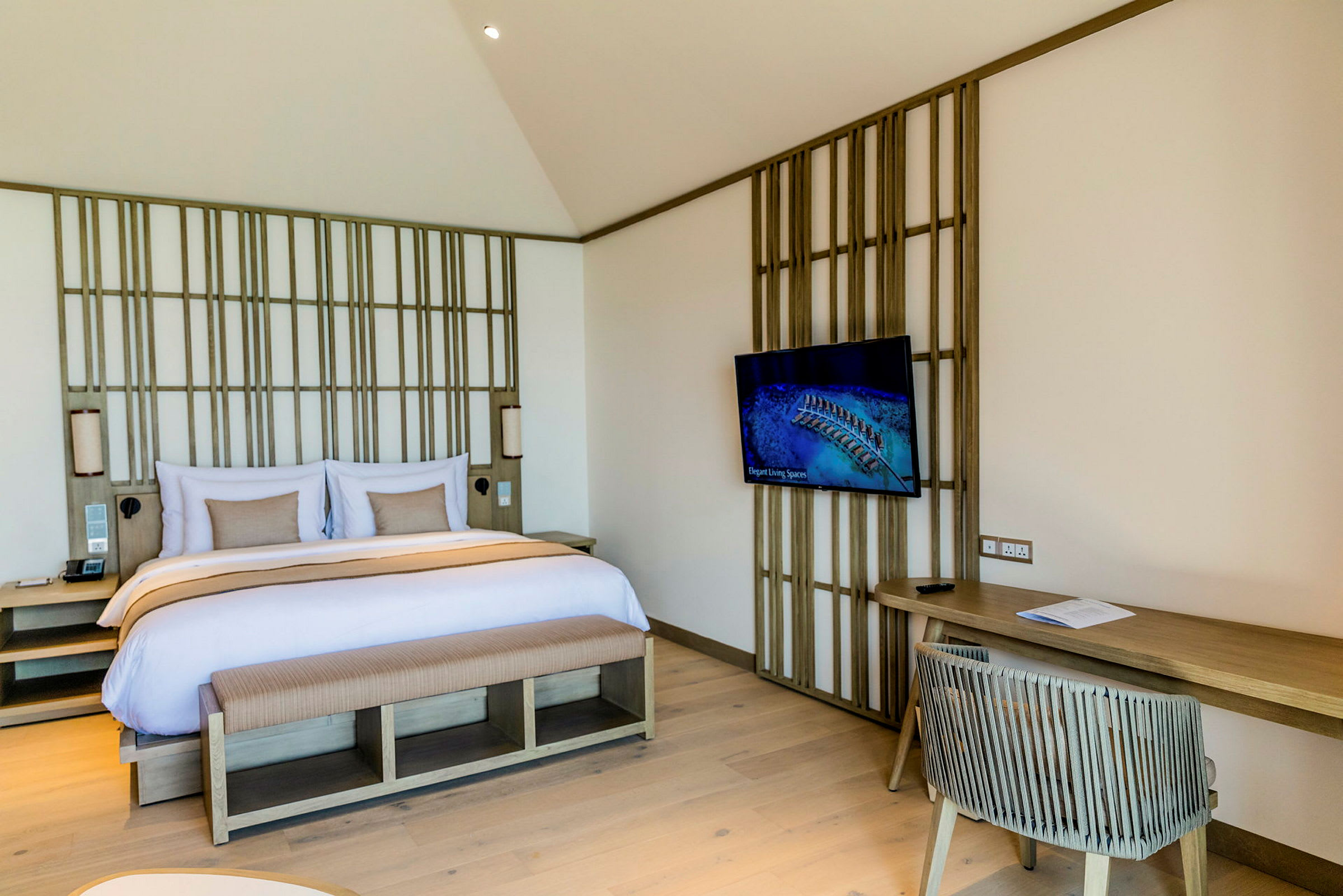 Et hotellrom med en dobbeltseng, TV på veggen og skrivebord med stol. (AI-generert tekst)